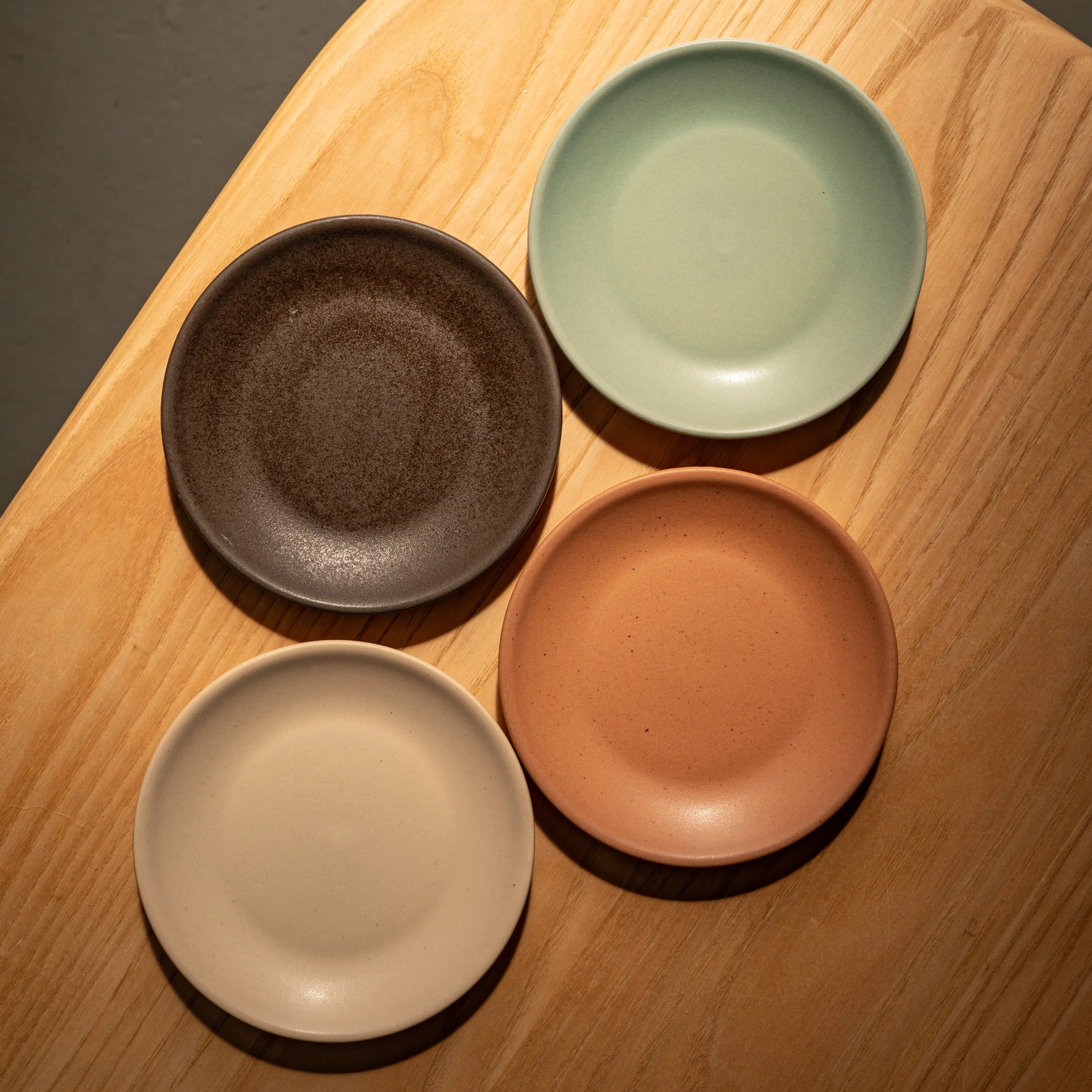 Mole, Agave, Dove, and Shallot porcelain plates grouped on a wood surface | Myrth Ceramics