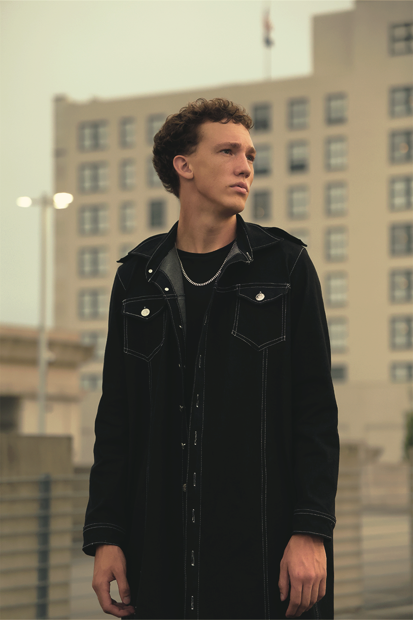 Action shot of man wearing VRTY clothing standing on top of parking garage