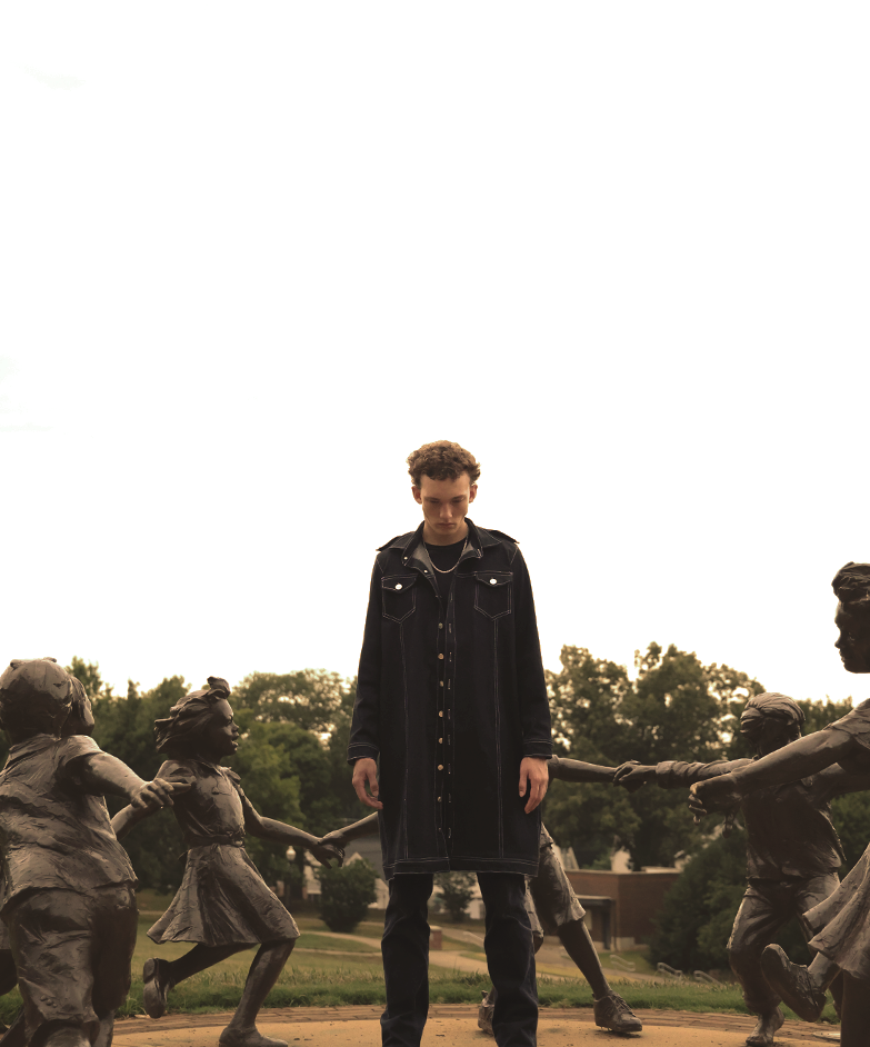 Cinematic shot of boy wearing VRTY clothing standing in the center of a group of statues