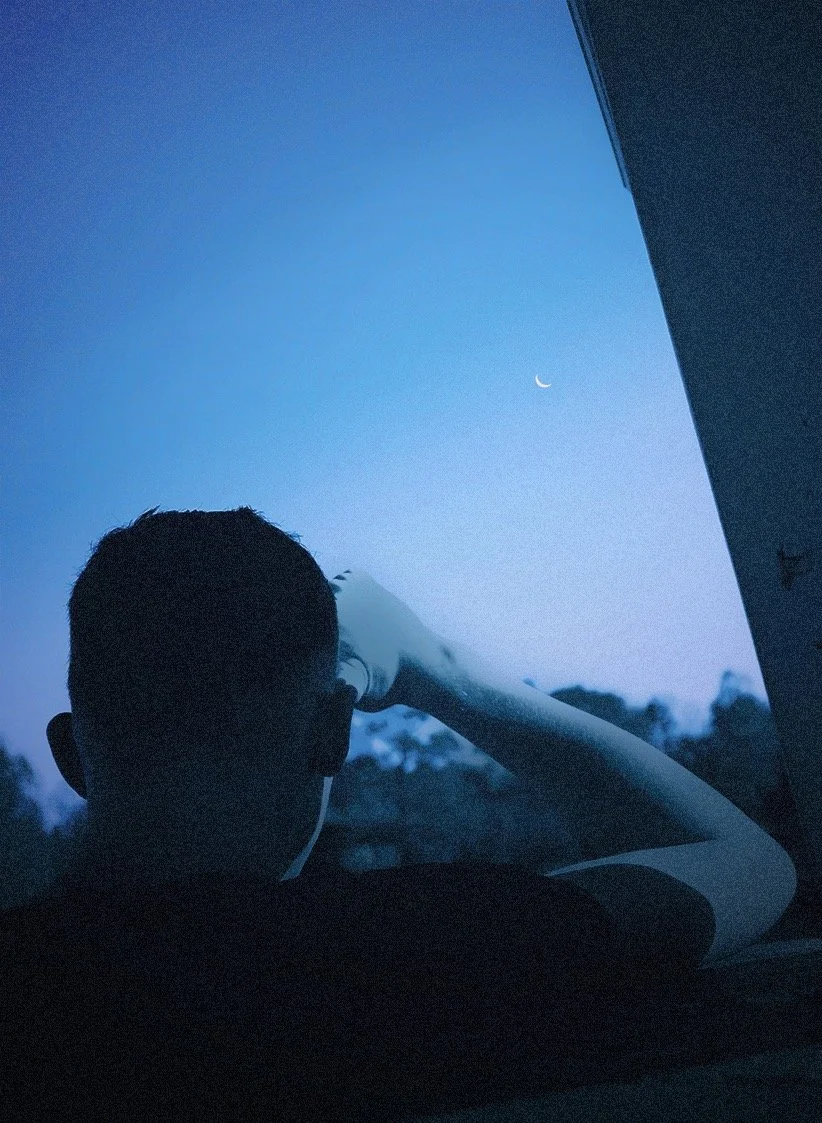 A boy staring at the moon during blue hour lighting
