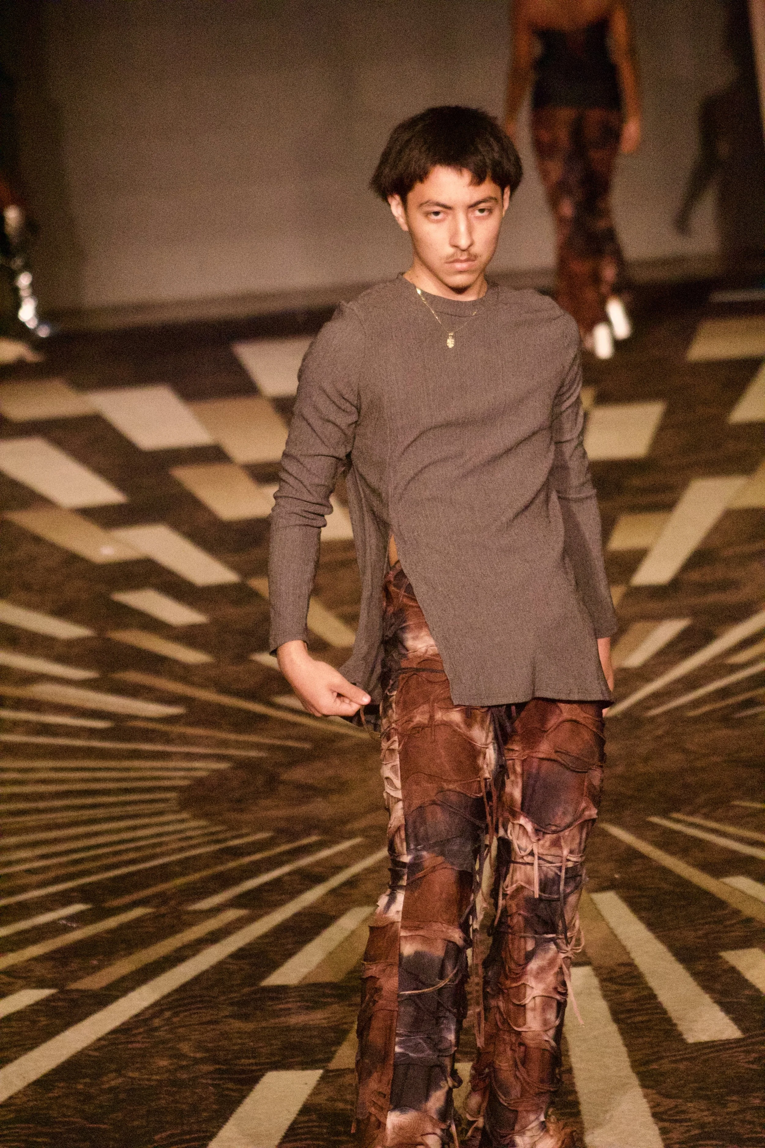 Model posing wearing neutral colored outfit on runway