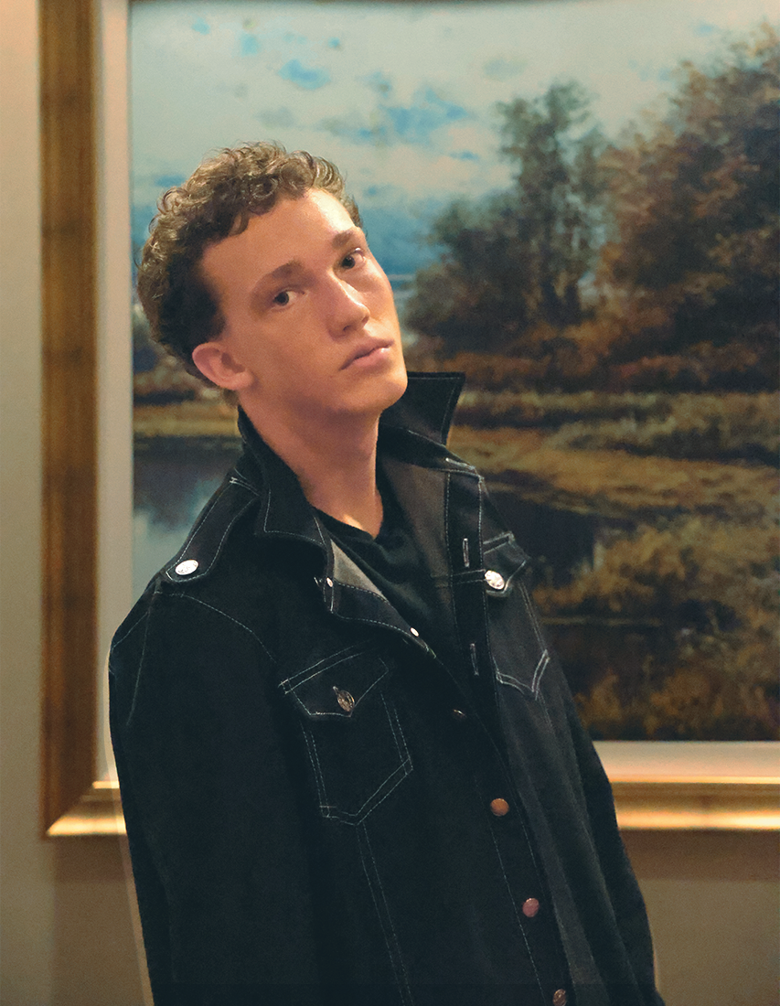 Boy standing in front of picture looking at camera