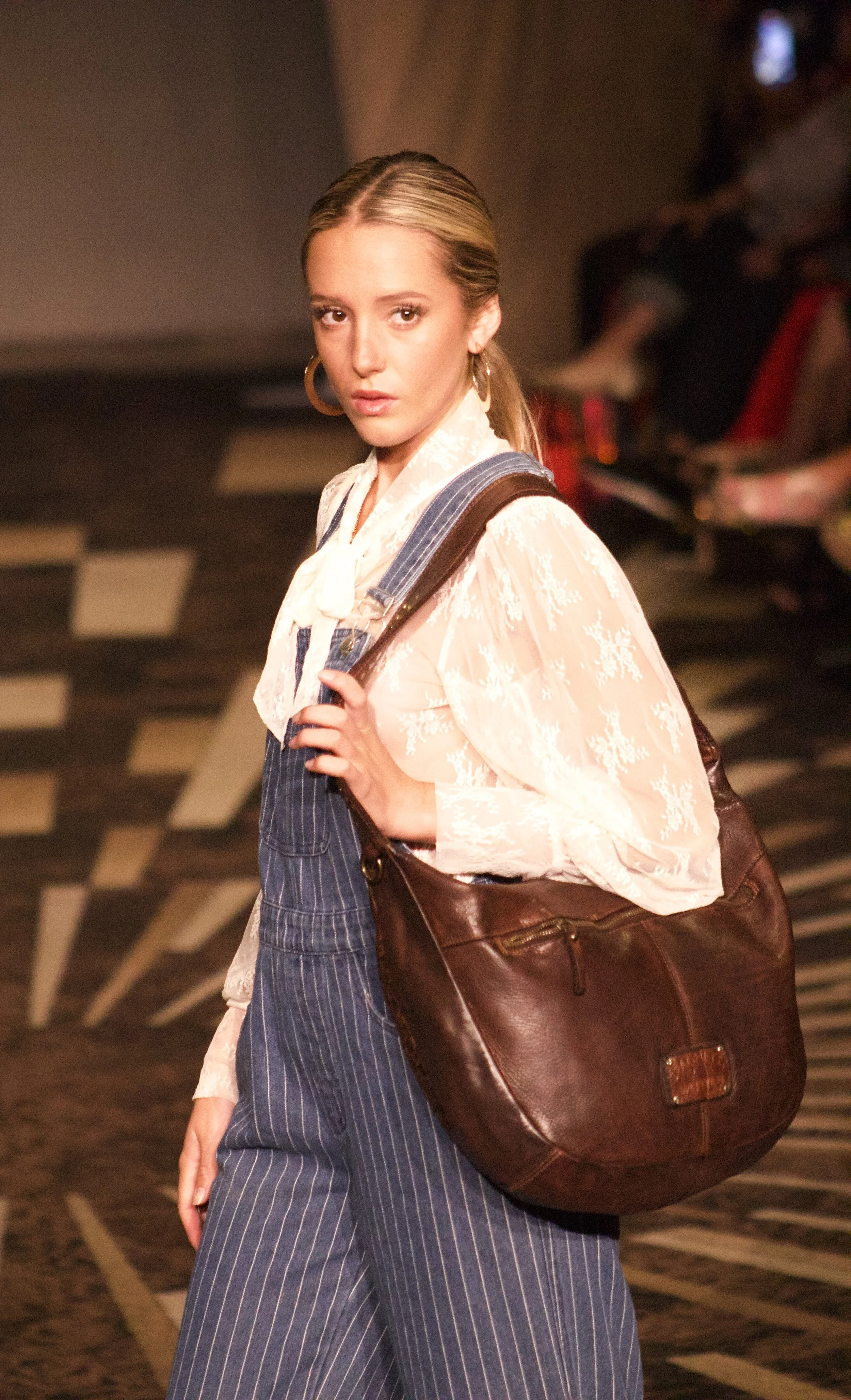 Model holding brown leather bag on runway