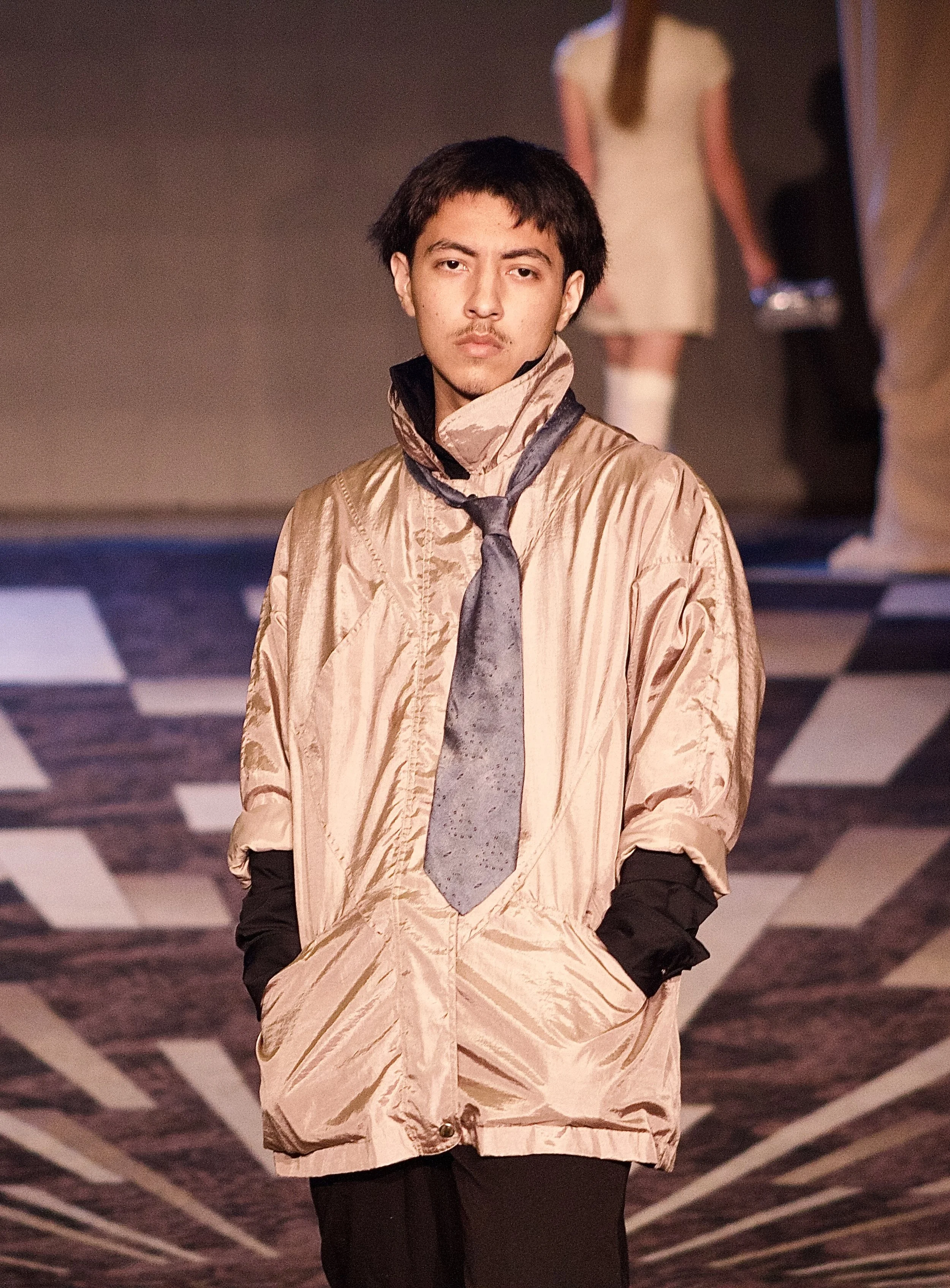 Young male model posing in loose fitting garment on runway