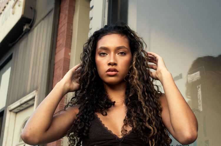 Model with curly hair posing beside building