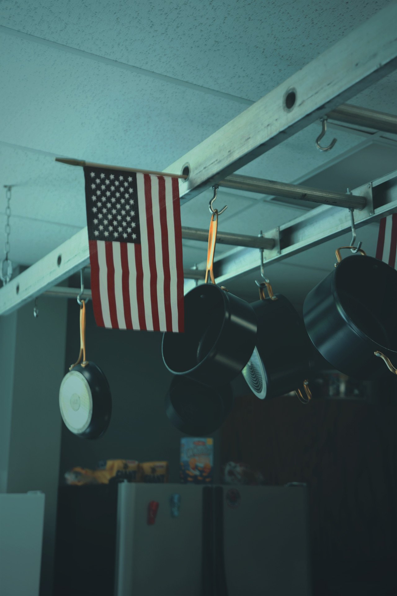 A lonely American flag hanging in a kitchen immersed in dim blue hour lighting