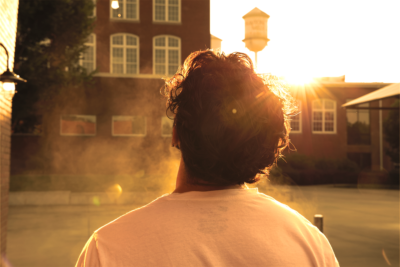 Young man basking in light with a halo glowing around him during golden hour lighting