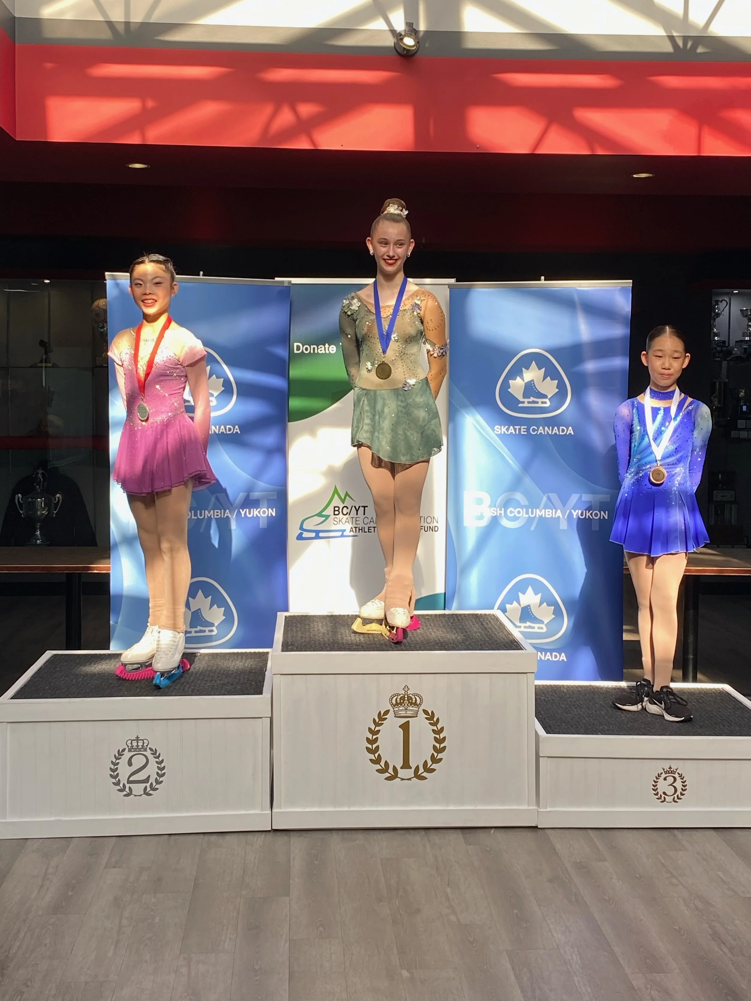 Three figure skaters take to the podium at the BC/YT high performance competition in June 2024