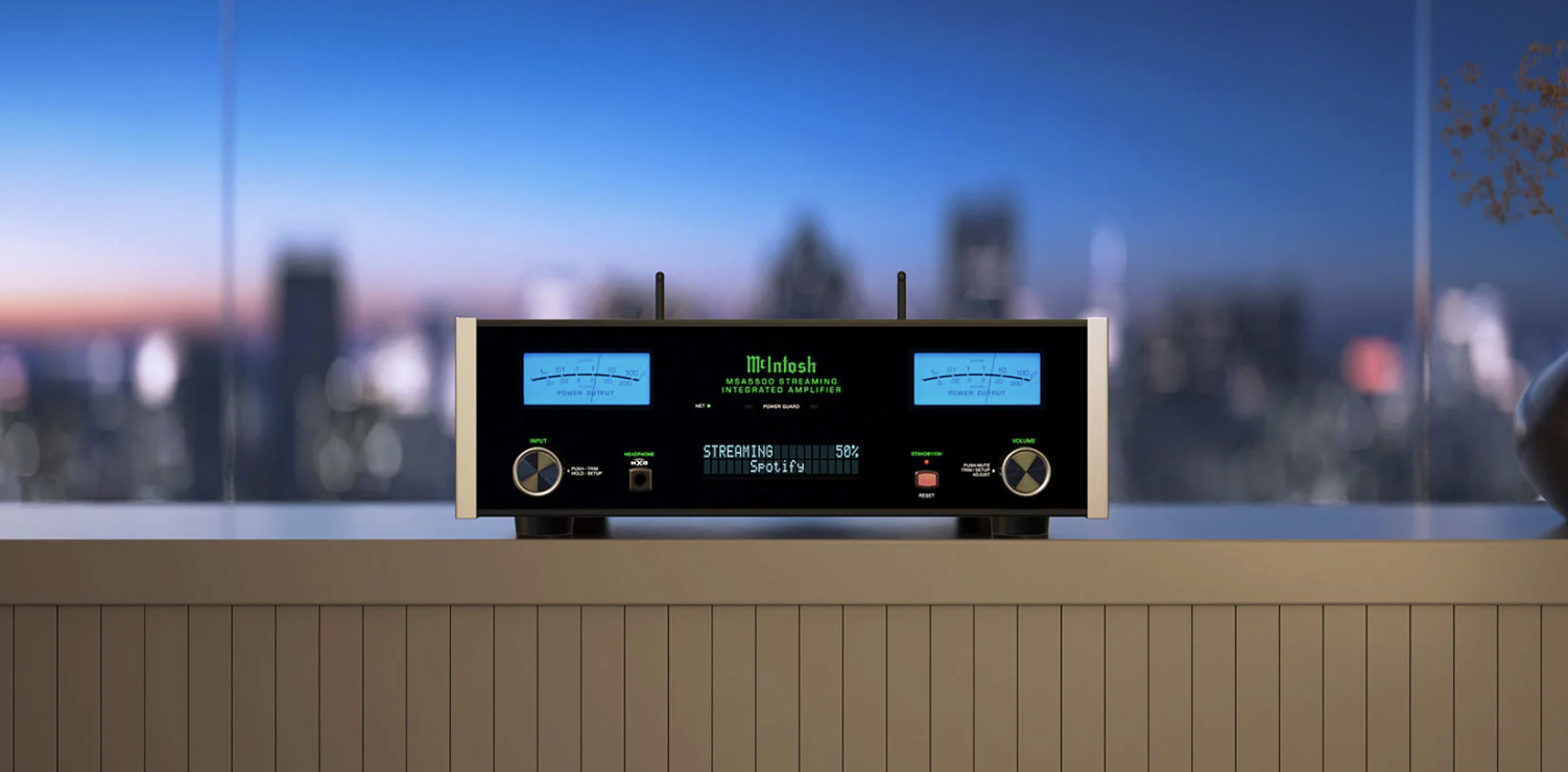 A  McIntosh stereo amplifier placed on a wooden surface with a city skyline and sunset in the background.