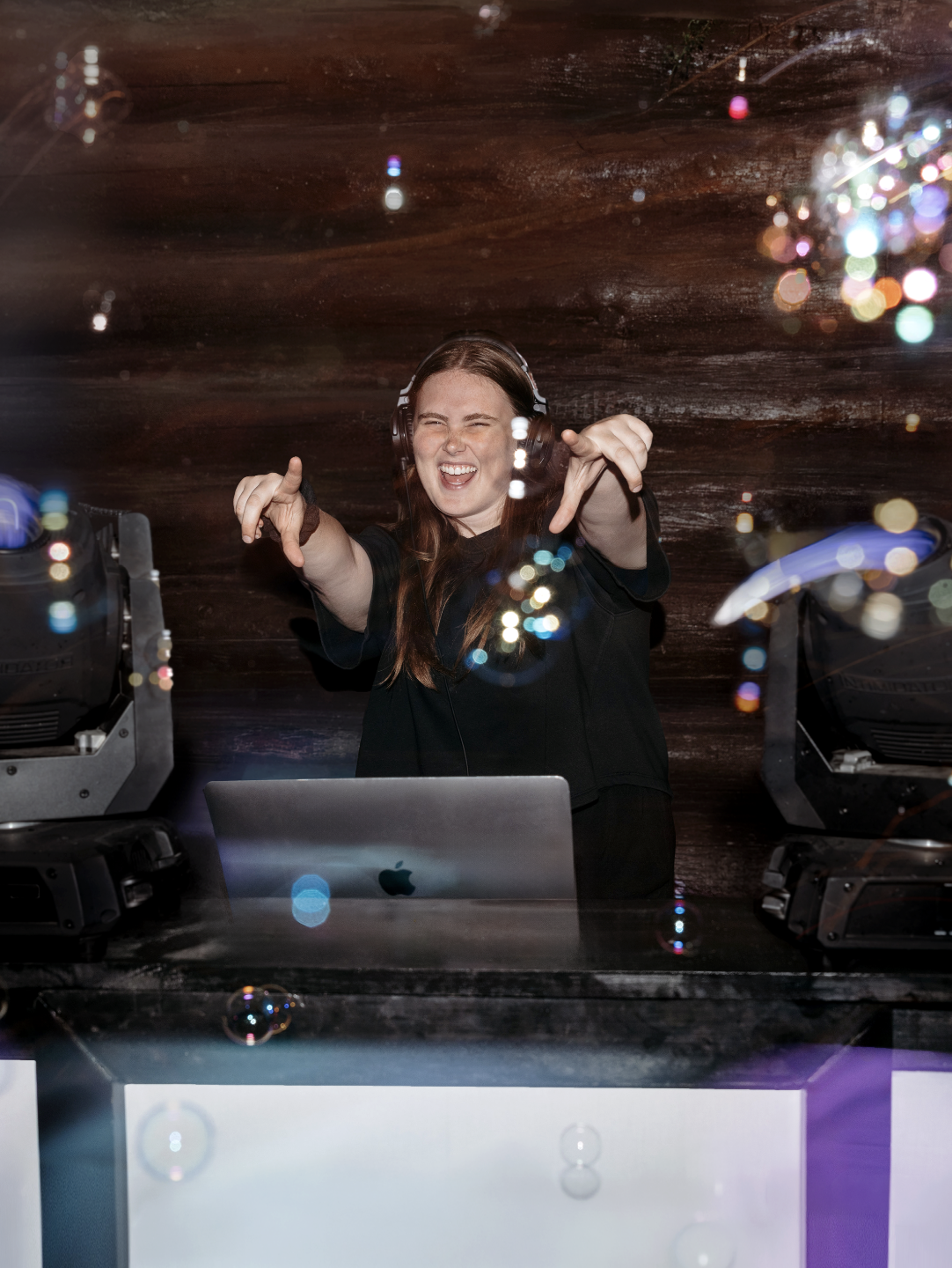 CC from Brown Sound performing at the DJ booth with stage lights in the background