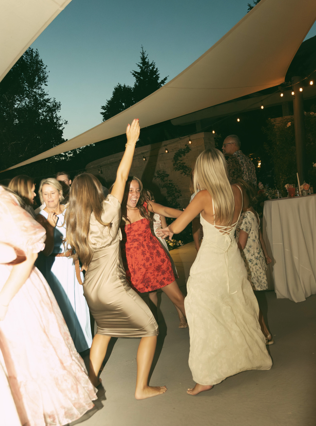 Wedding guests dancing outdoors under string lights at a Utah reception