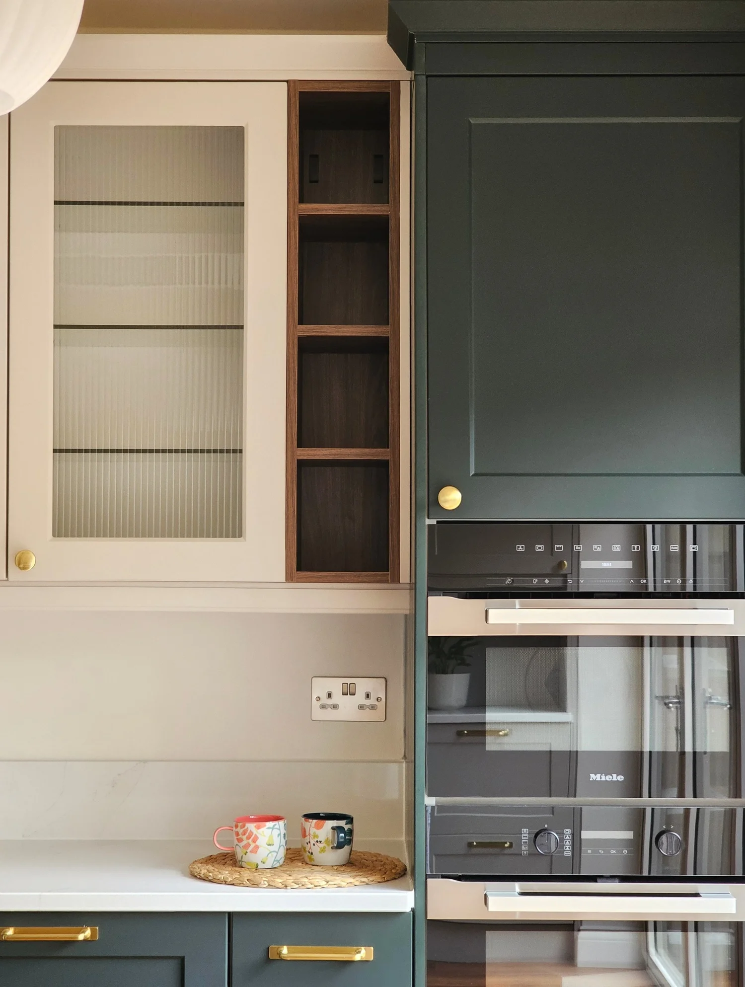 Fluted glass wall cabinet in a deep green kitchen