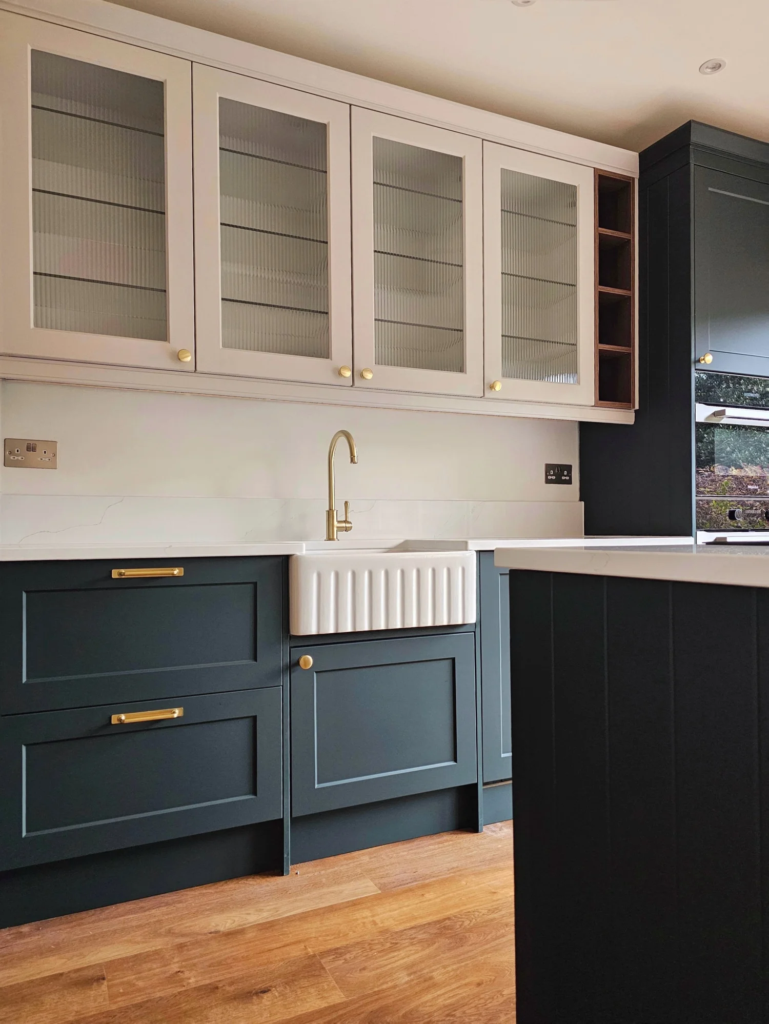 Deep green cabinetry and oak feature in a family kitchen