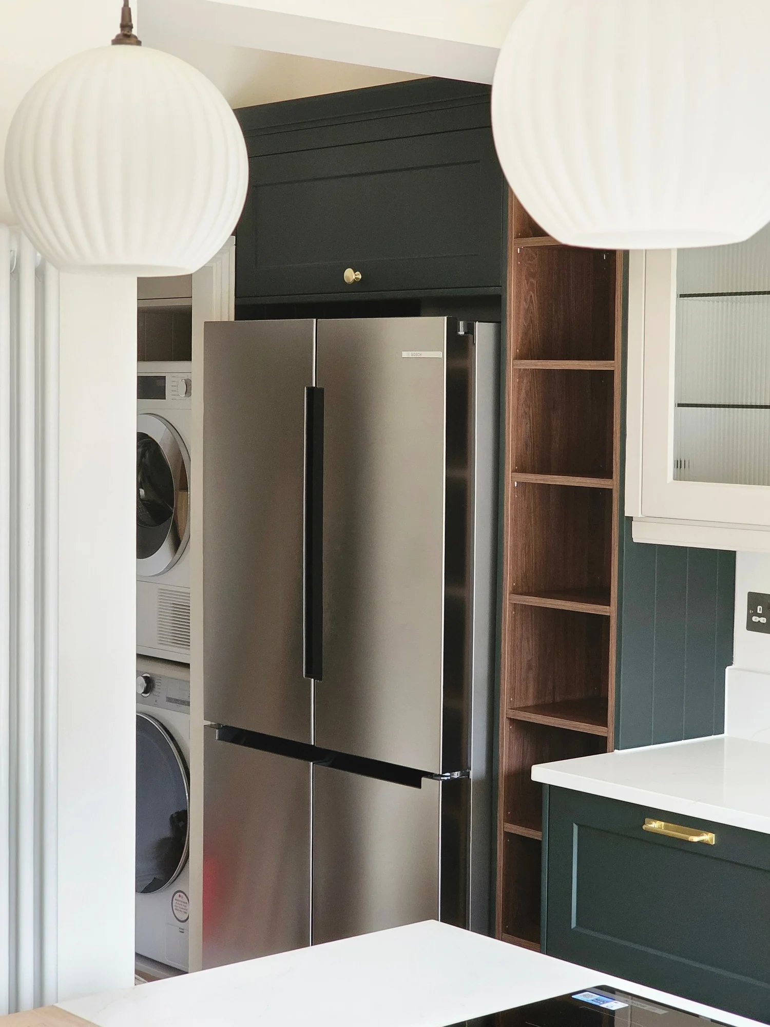 Brass handle and oak detail on deep green cabinetry