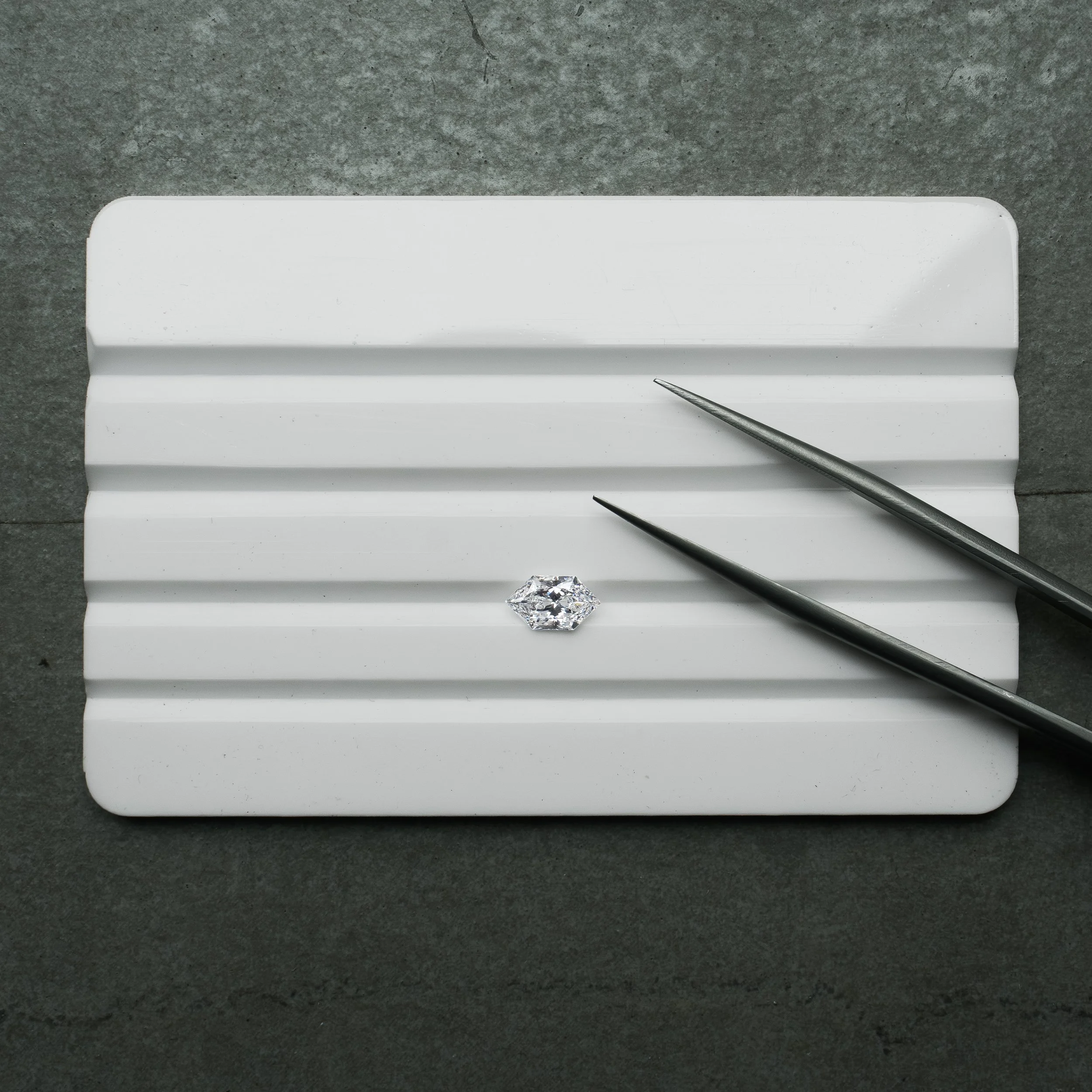 Loose Dutch-cut marquise brilliant diamond on a white grooved tray with gem tweezers.