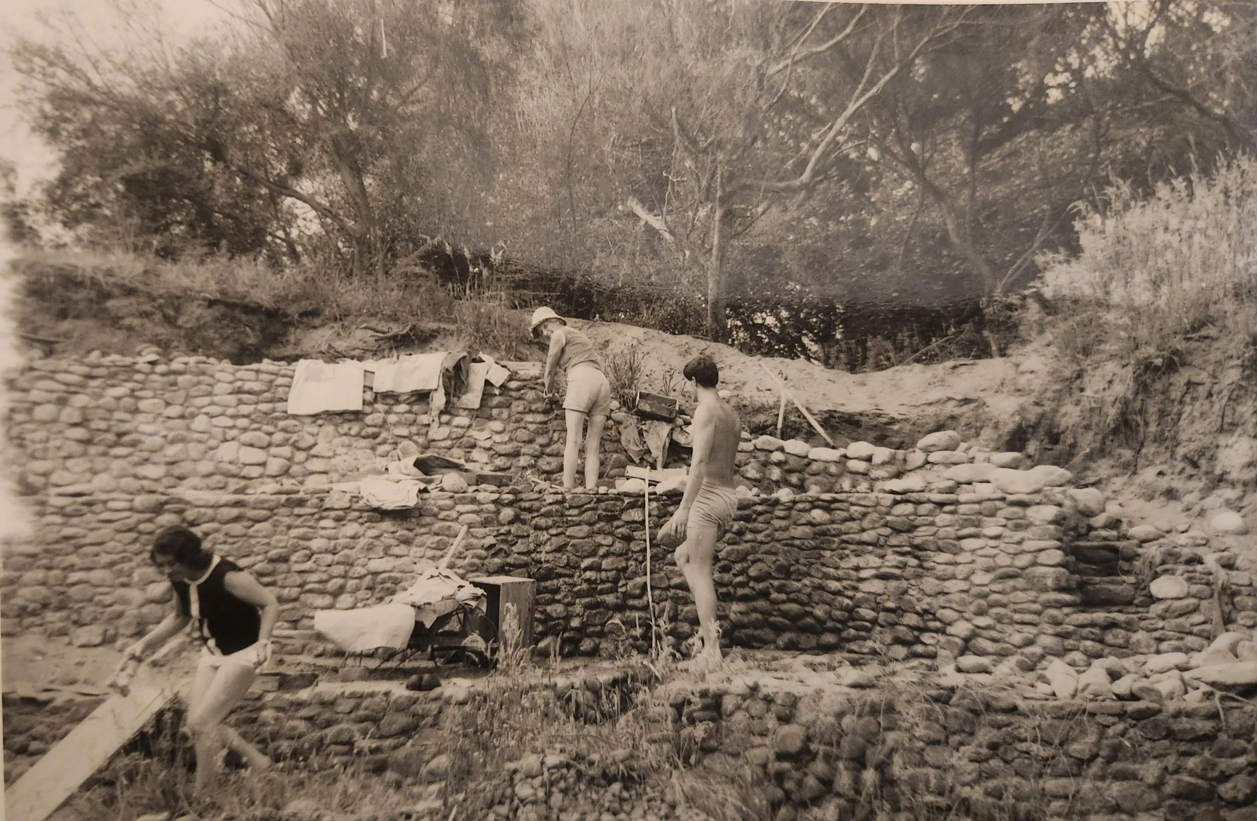 1960s, 44 Tasman Rd. Marly building her stone walls, Nick helping, Andy trying to get out of the photo!