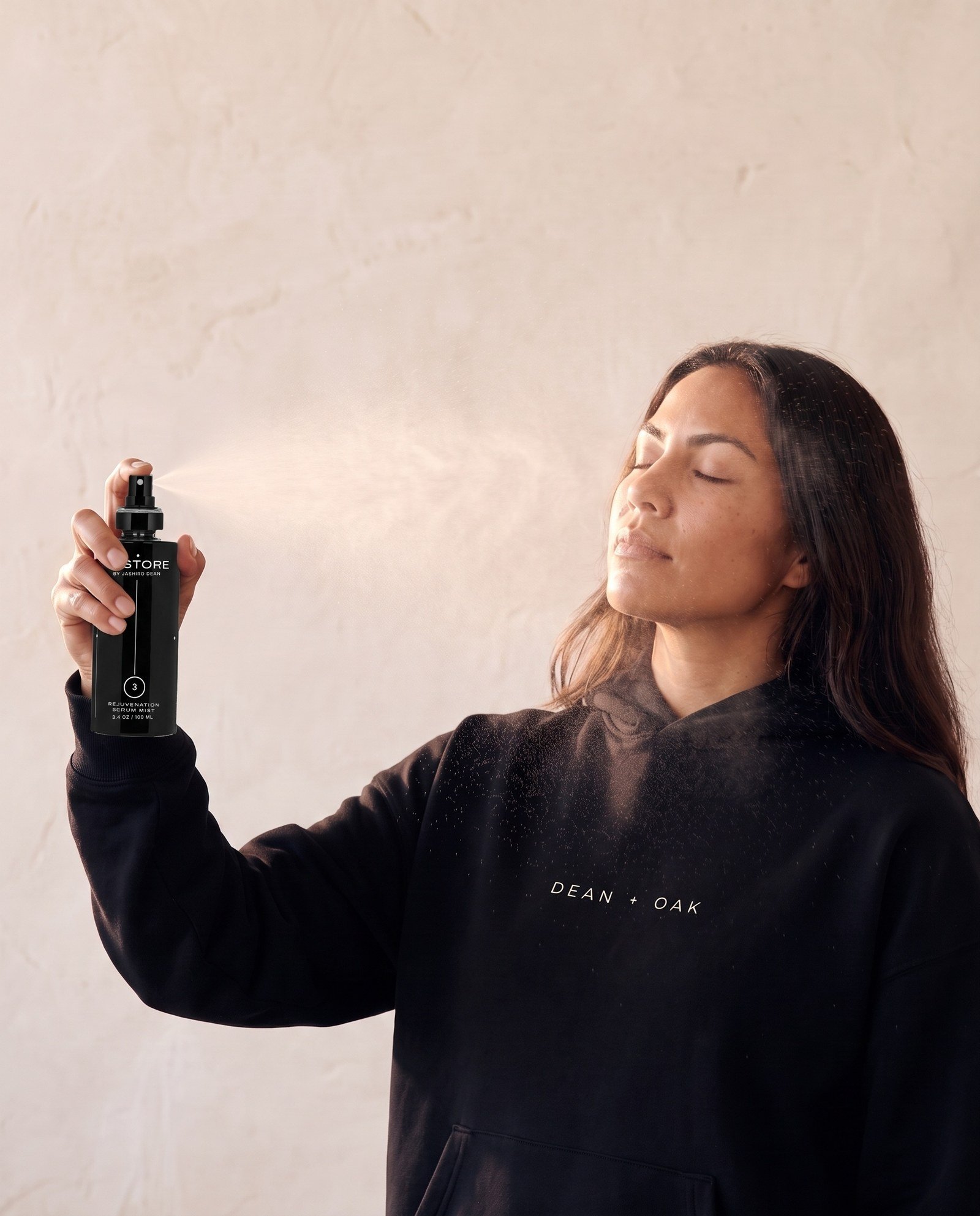 Dean + Oak RESTORE Rejuvenation Serum Mist, held by a model