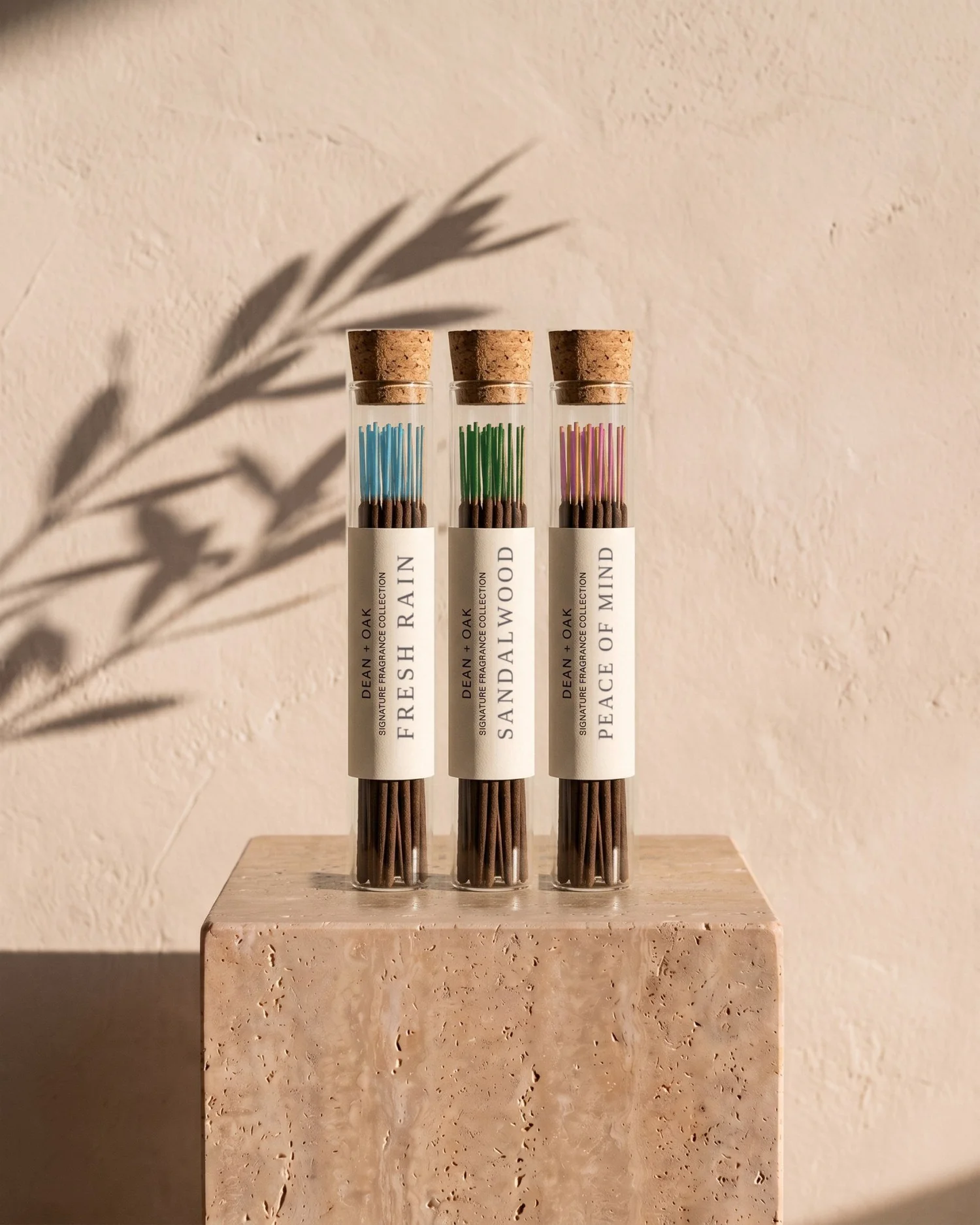 Three corked tubes of Dean + Oak incense on a travertine plinth