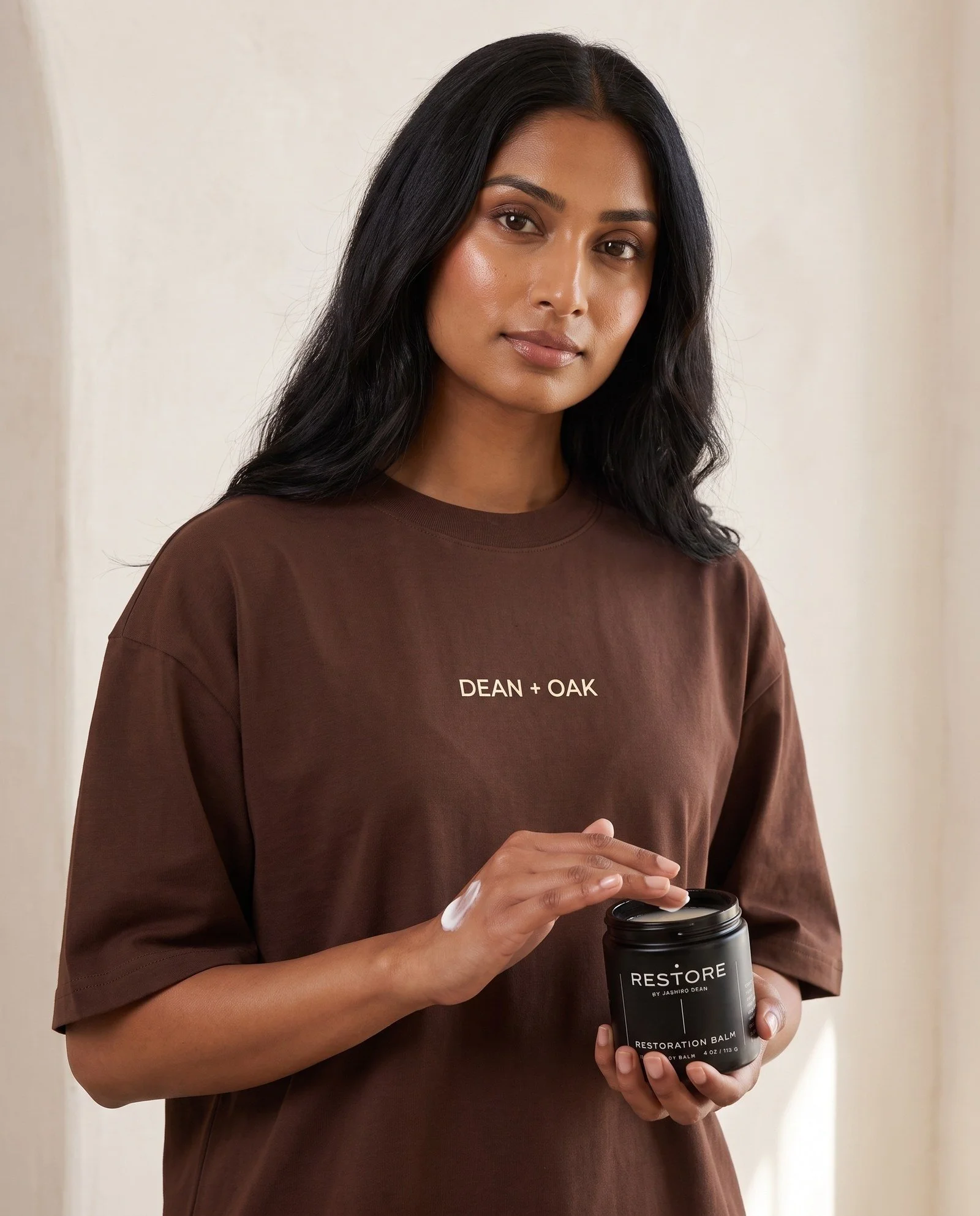 Dean + Oak RESTORE Restoration Balm, held by a model