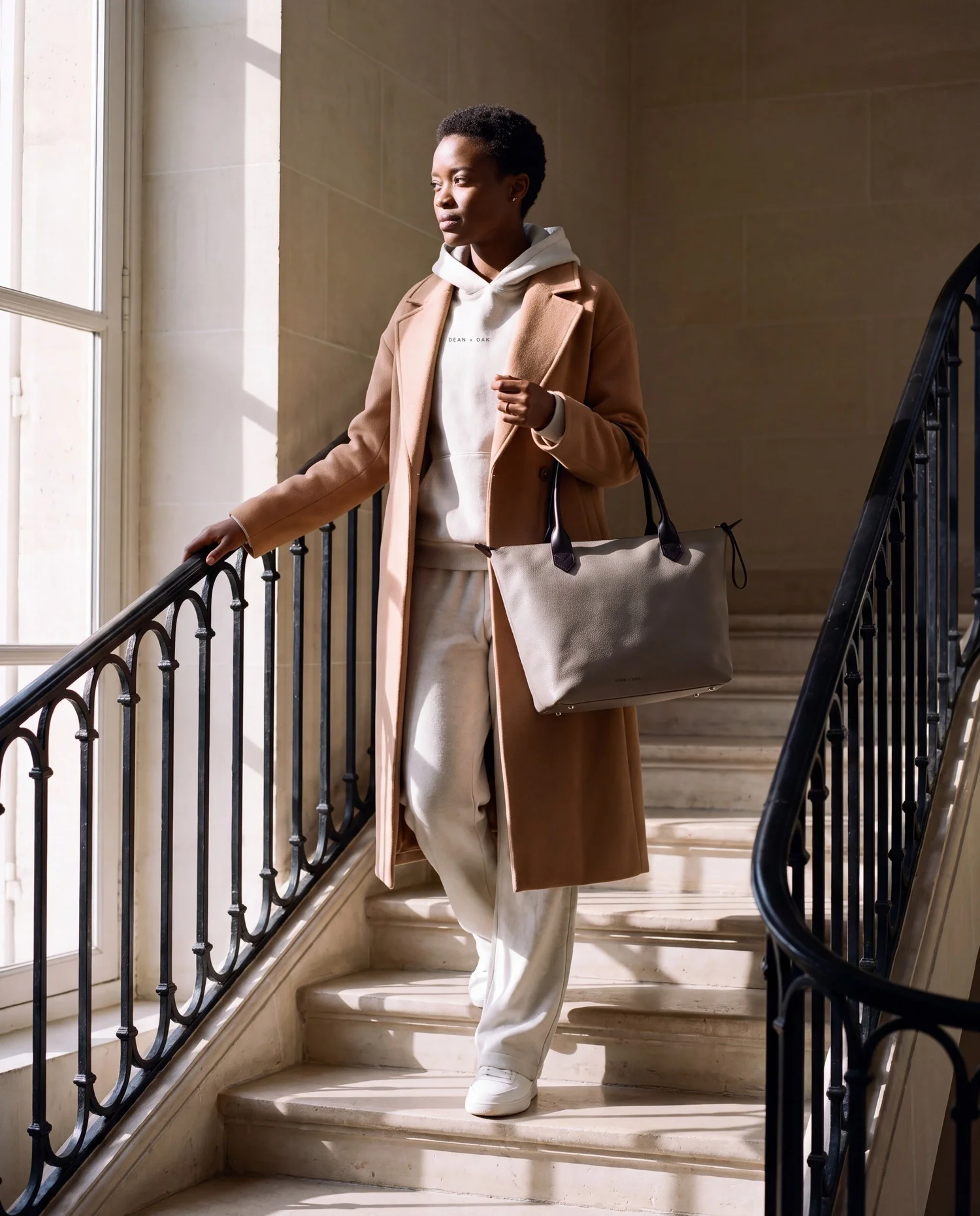 A woman on a Paris staircase with The Tote in Oat