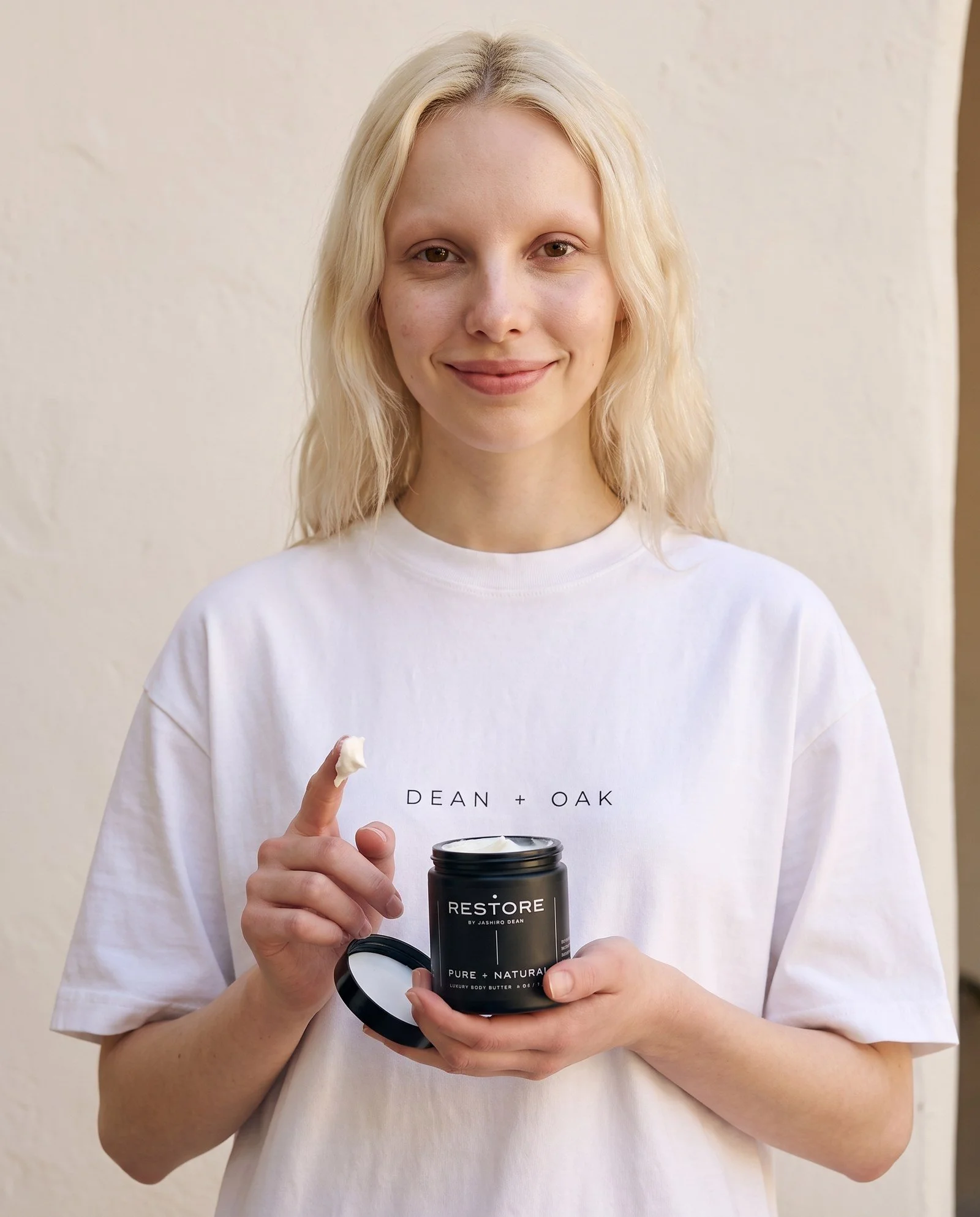 Dean + Oak RESTORE Pure + Natural Body Butter, held by a model