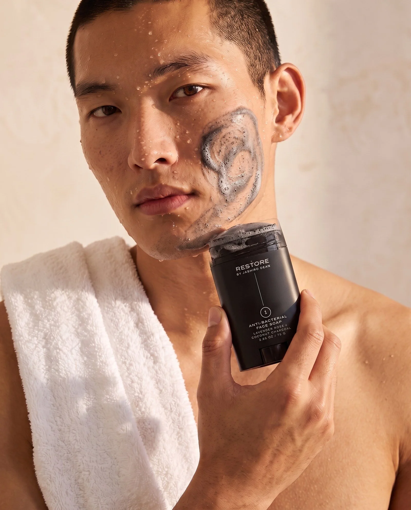 Dean + Oak RESTORE Anti-Bacterial Face Soap in Charcoal, held by a model
