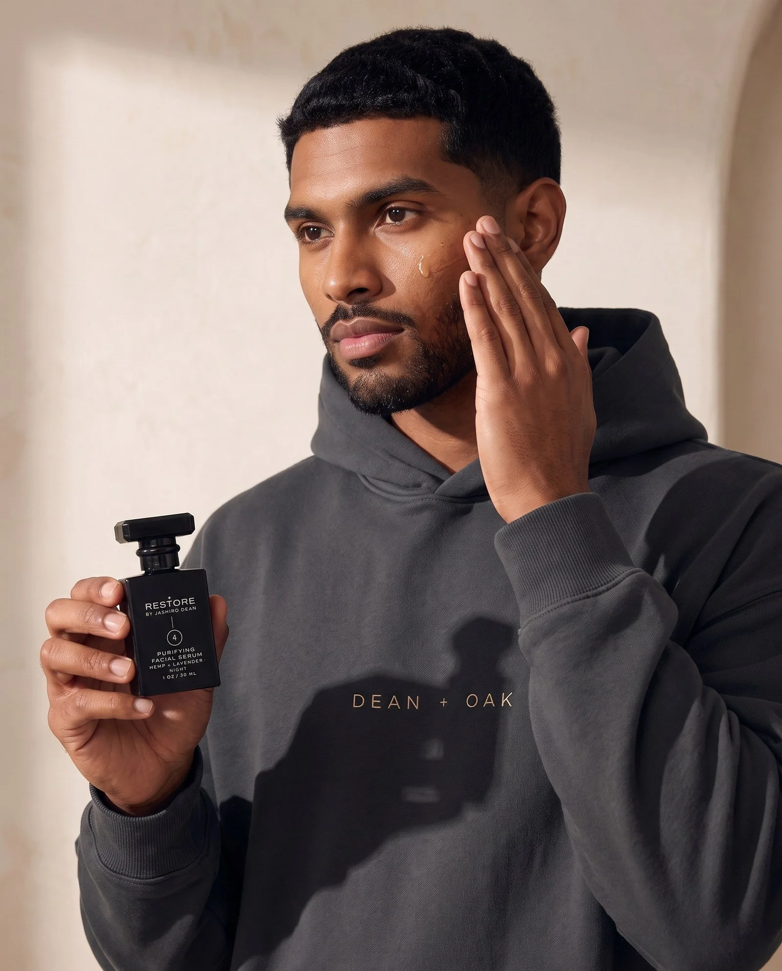Dean + Oak RESTORE Purifying Facial Serum, held by a model
