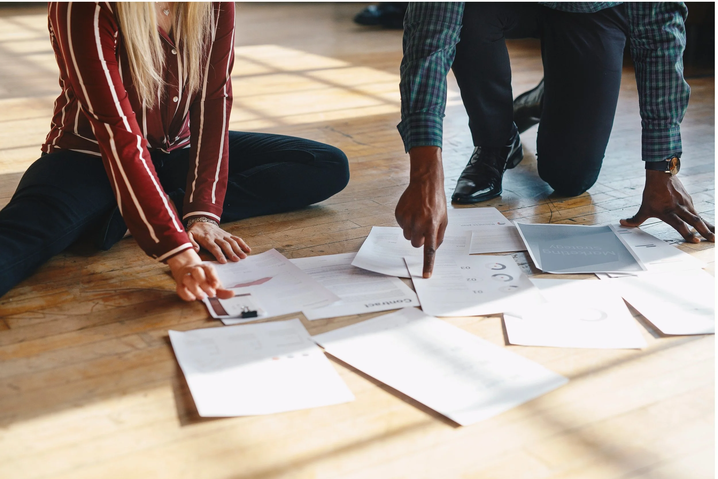 Photo of two adults sorting a pile of paperwork on the floor at home