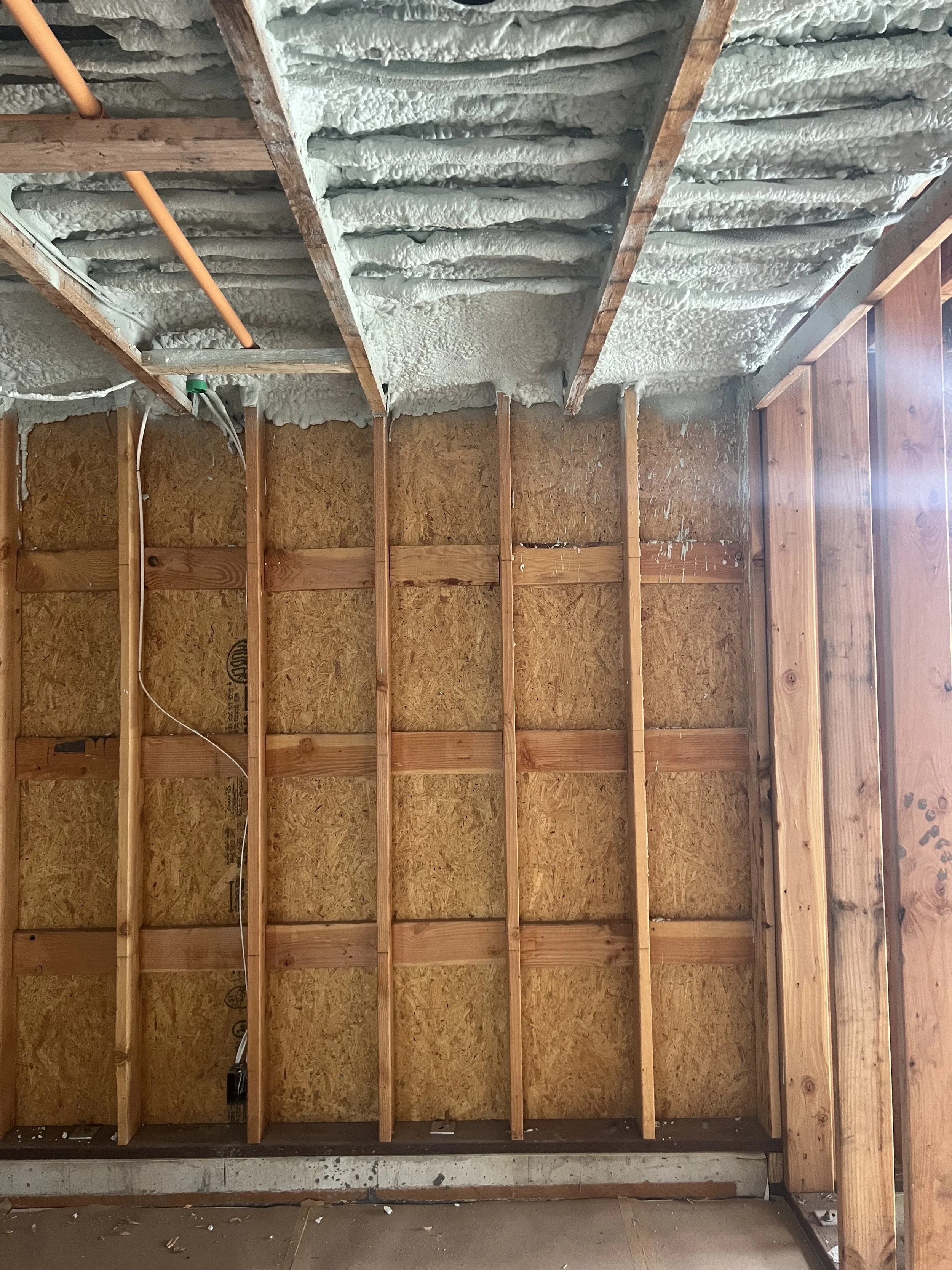 Interior of a garage with exposed wooden studs and insulation on the ceiling.