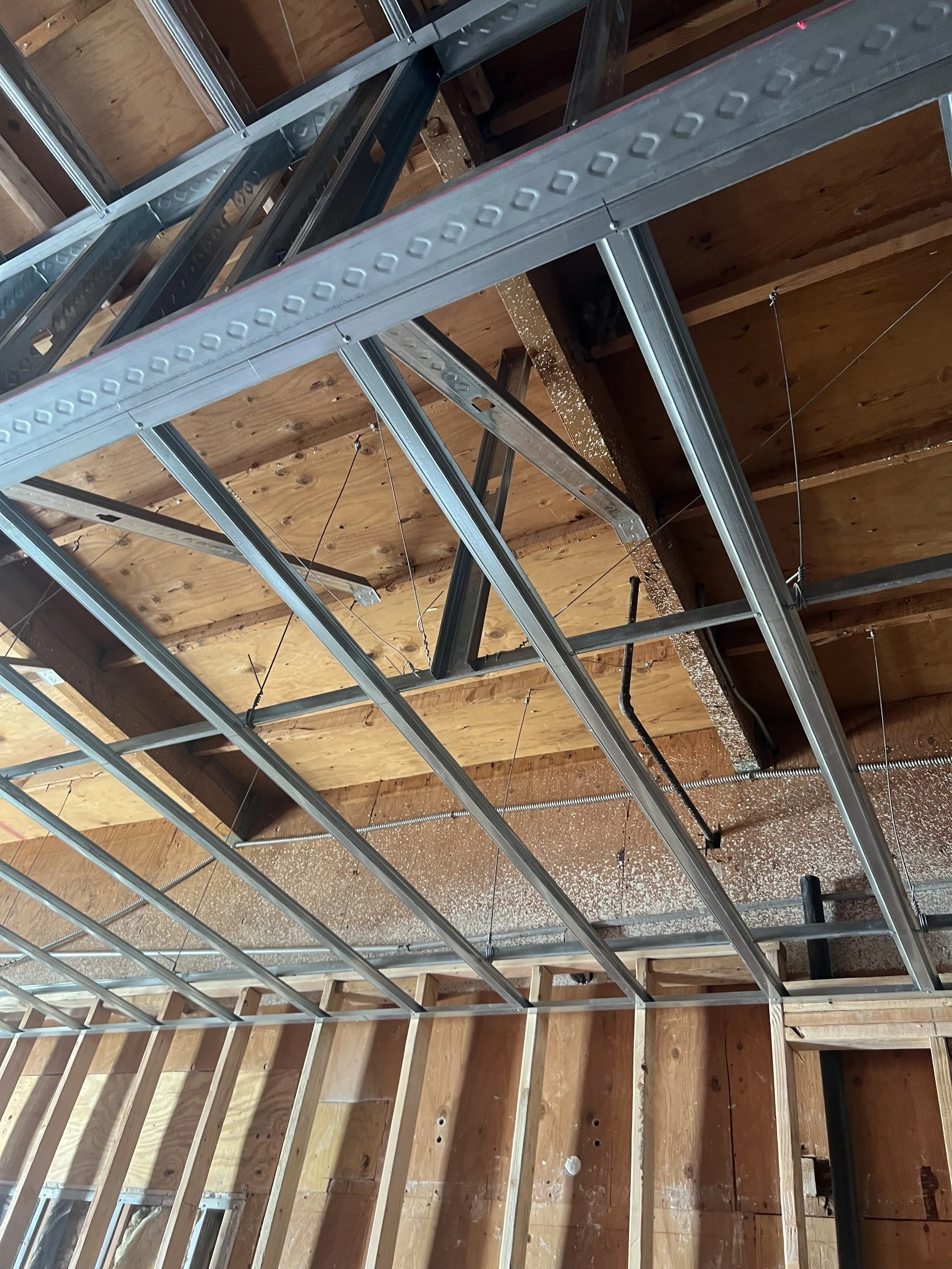 Interior view of a construction site showing metal framing and wooden ceiling and wall structures.