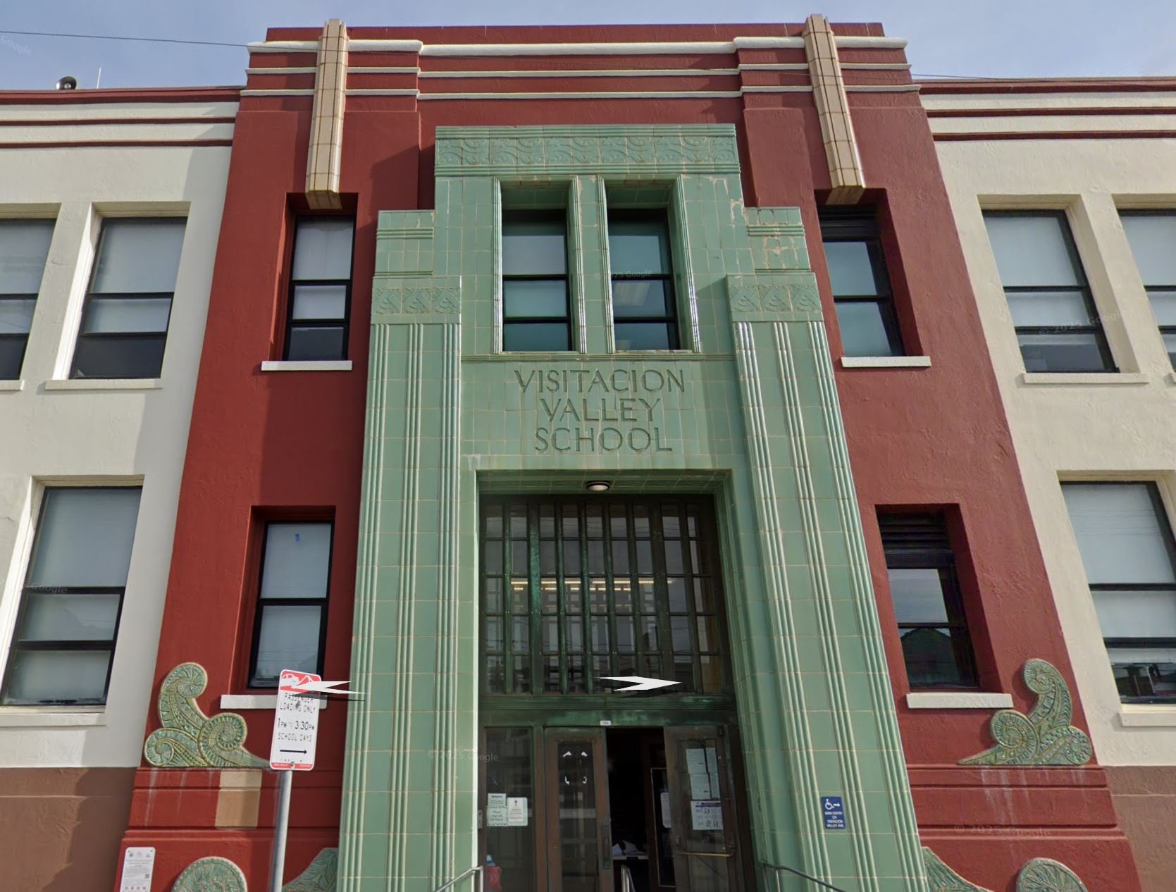 The entrance of Visitation Valley School, showcasing a facade with art deco architectural style, green decorative tiles, and red and cream walls.
