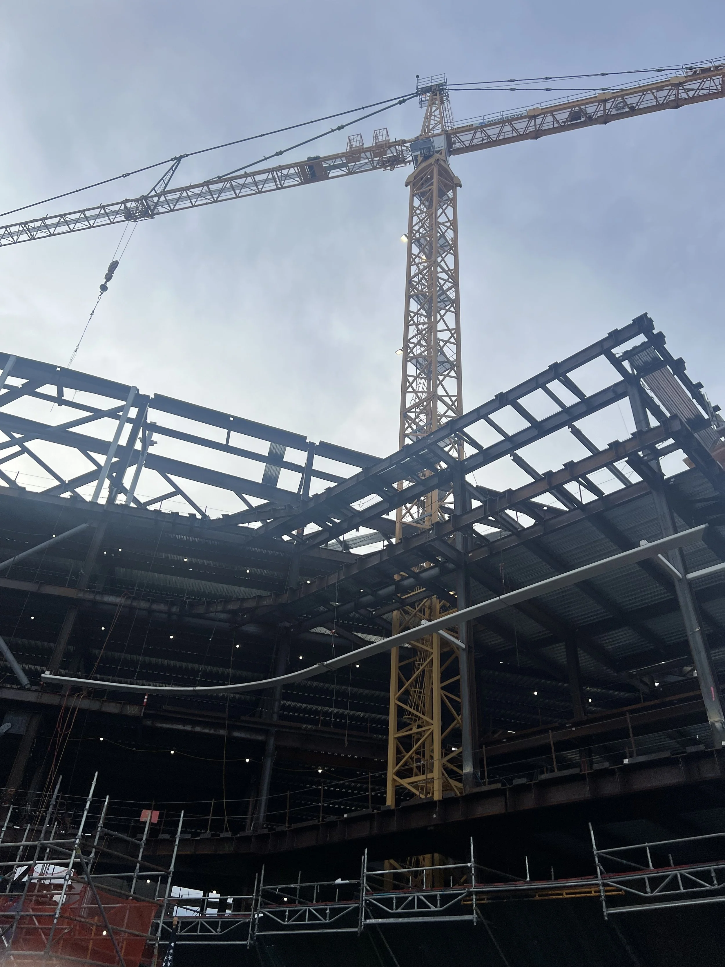 A construction site with a large yellow crane and a building framework under construction.