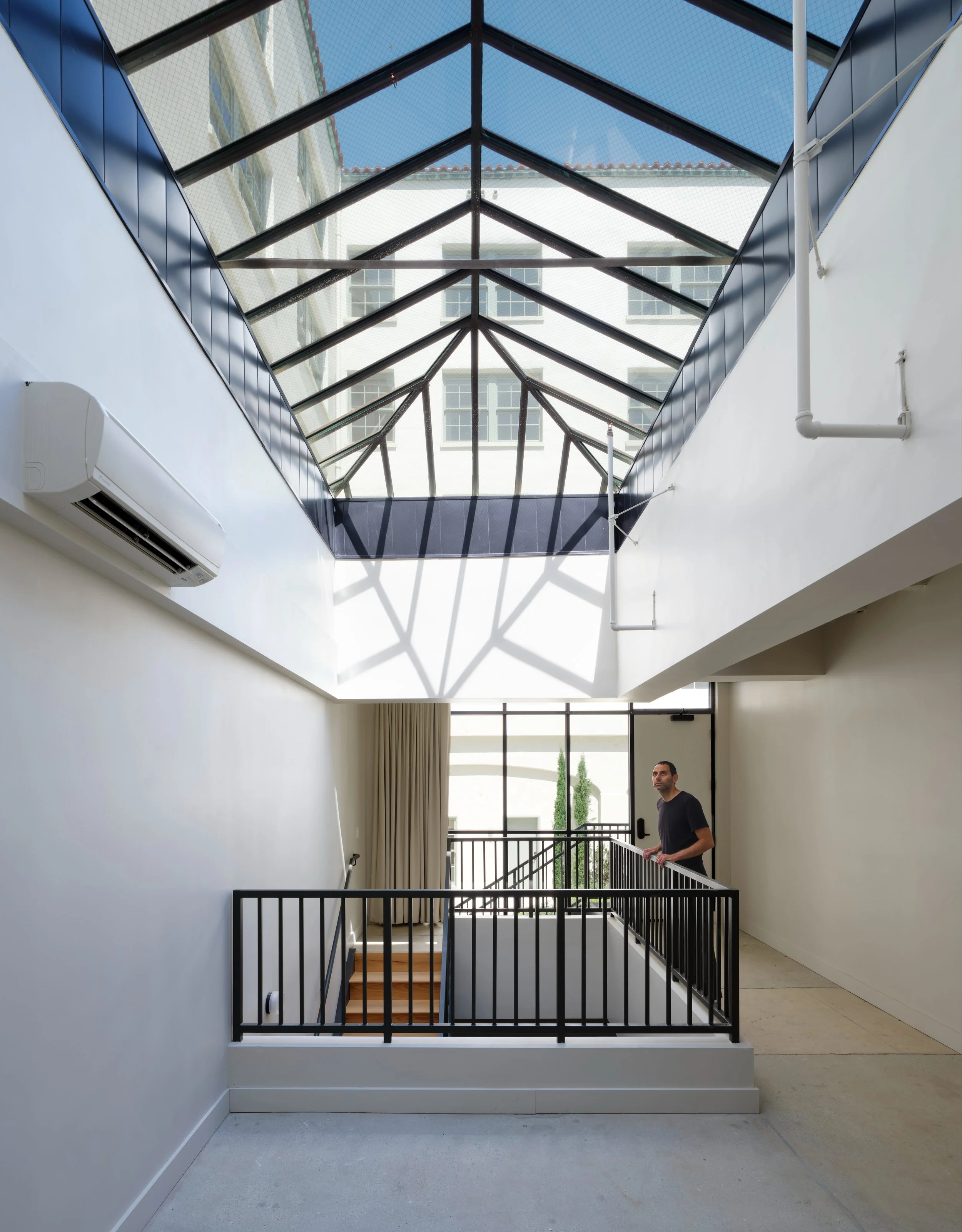 Bringing Light to the Core. Deep floor plates in historic buildings often struggle with natural light. We restored the original steel-truss skylight system to flood the central atrium with daylight. This acts as the social heart of the building, wher