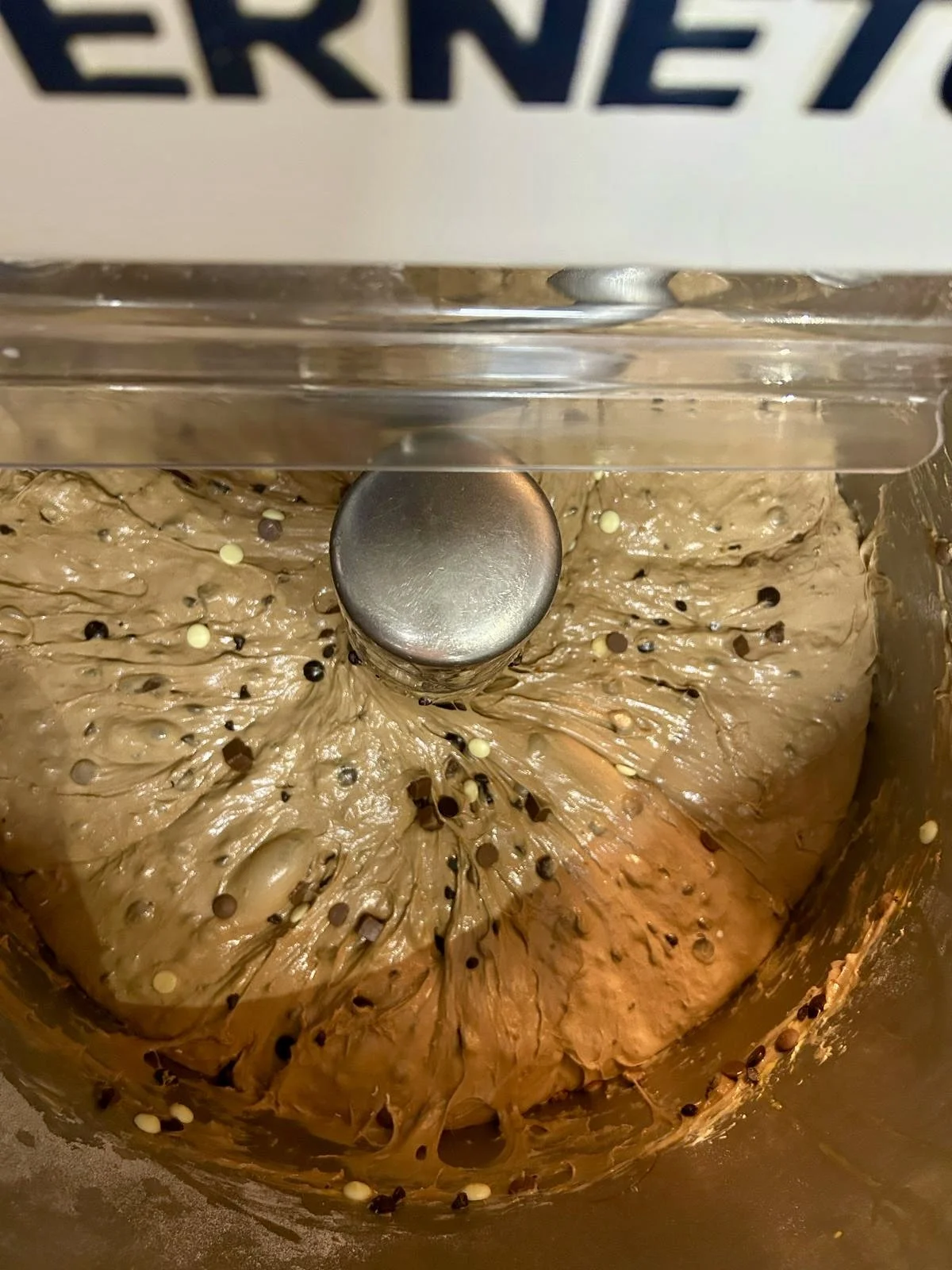 Masa de helado de chocolate en una máquina de helado con chispas blancas y oscuras.