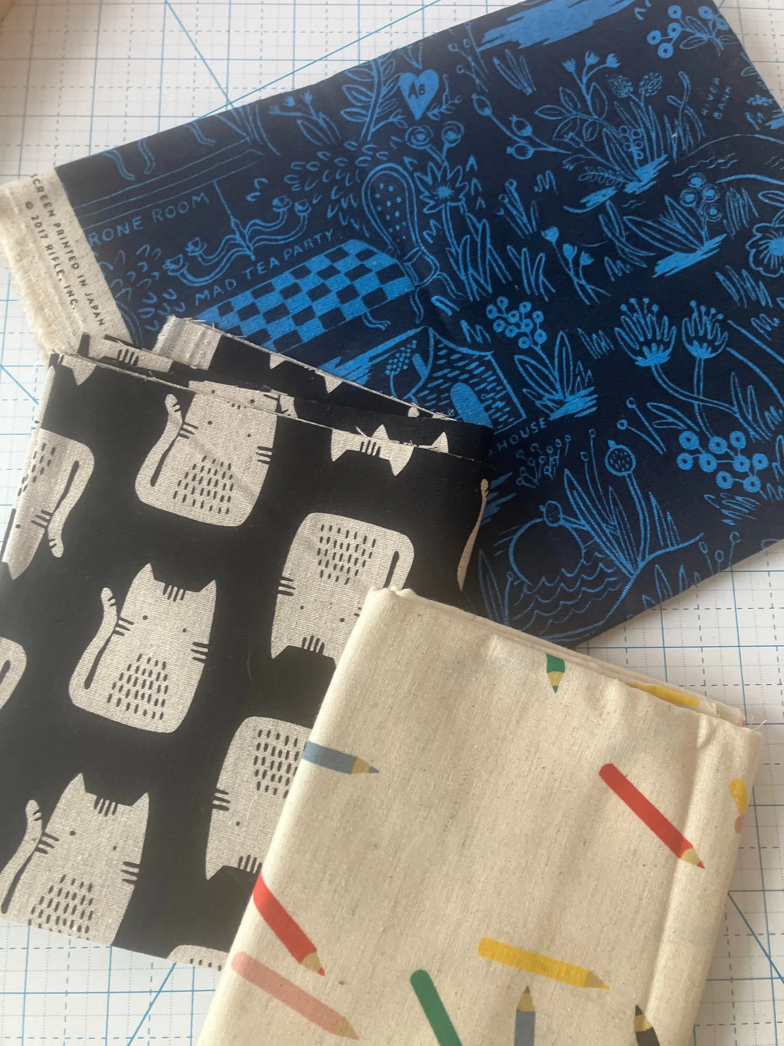 Stack of linen pieces of fabric from personal stash including cats and Rifle Paper Co