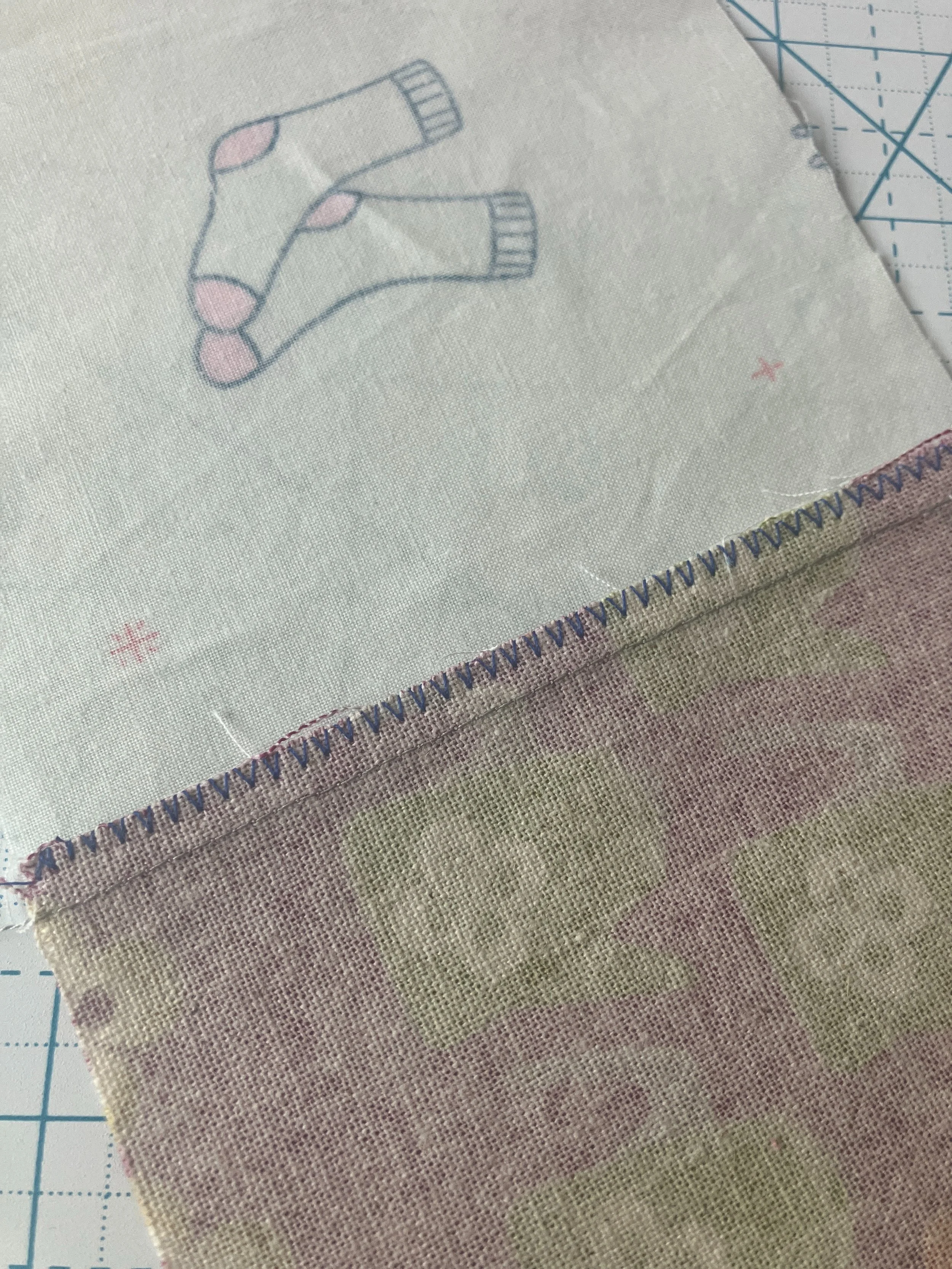 Close up photo of the back seam of two quilt squares with the seam pressed towards the quilting cotton.