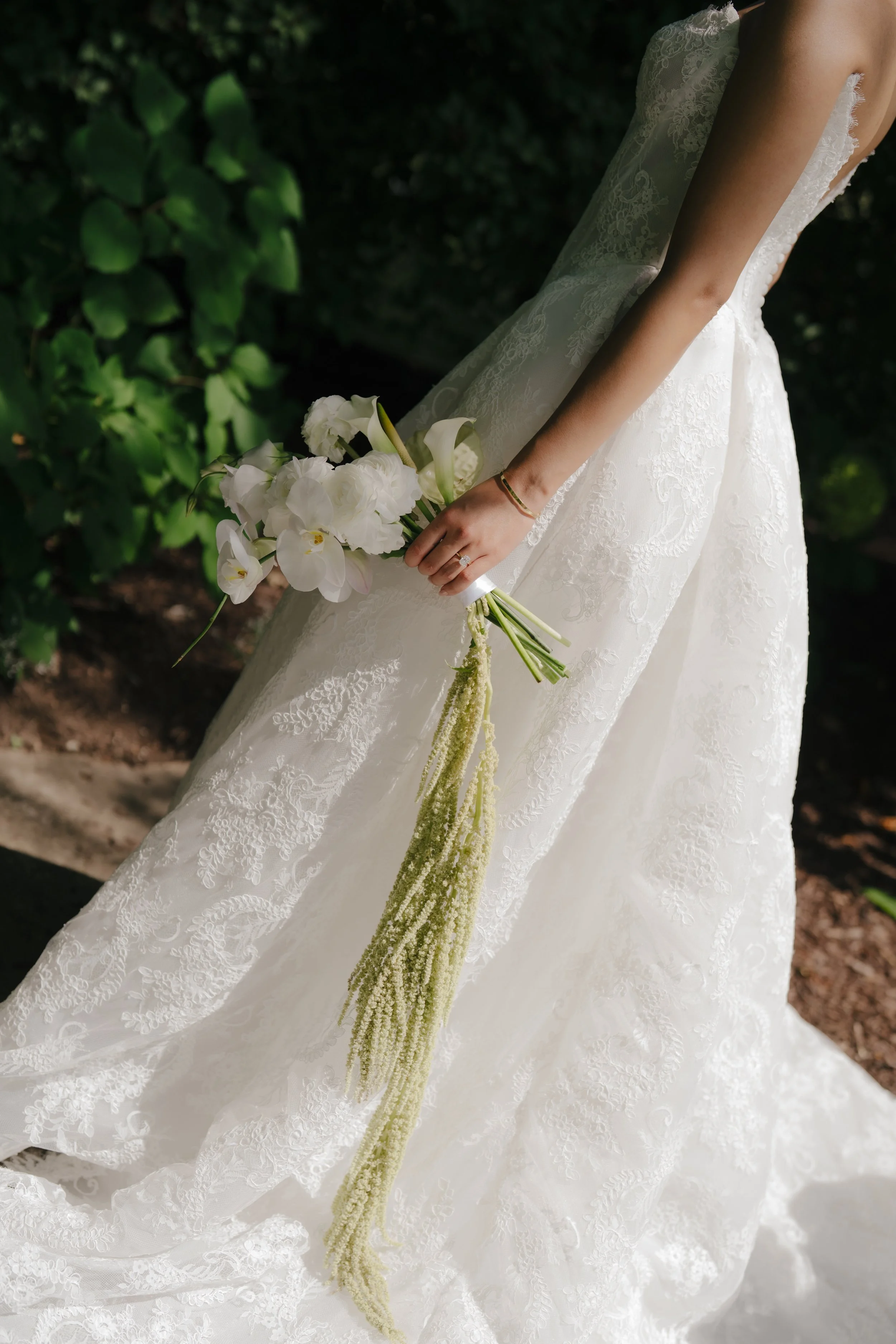 Luxury floral centerpiece with premium blooms styled by Dereves, Toronto wedding floral design expert. white flowers, including orchids and calla lilies, outdoors with green foliage in the background.