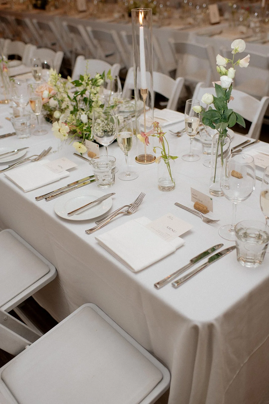 Elegant wedding reception table with white tablecloth, floral centerpieces, candles, and neatly arranged silverware and glassware in Toronto rental weddings