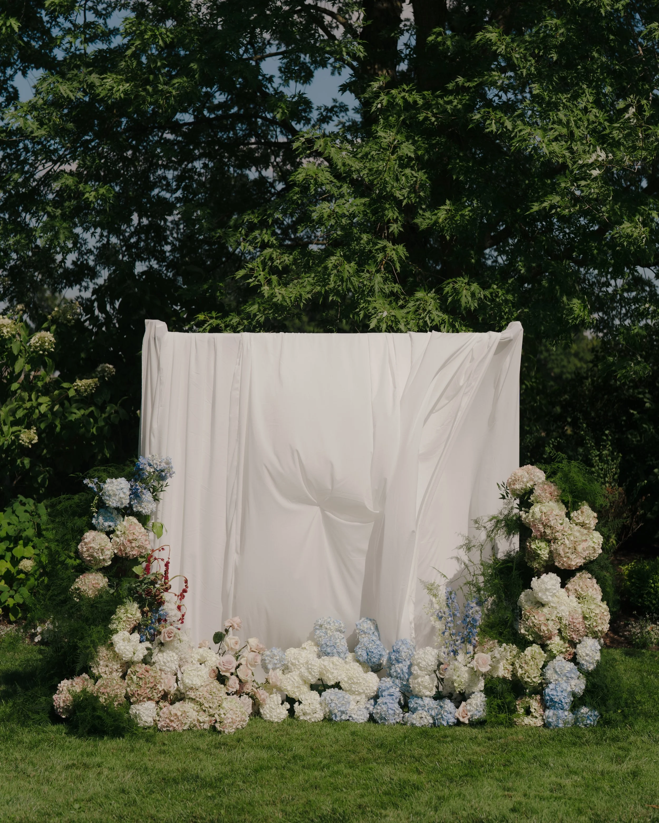 Elegant draped ceremony backdrop with soft white florals designed by Dereves Studio, Toronto wedding planner for luxury events
