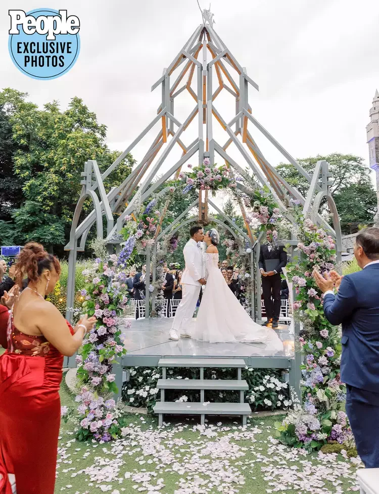A wedding ceremony taking place outdoors under a decorative archway adorned ceremony at Casa Loma | Best Luxury Toront Florist | Kiana and Lovell Luxury Weddings