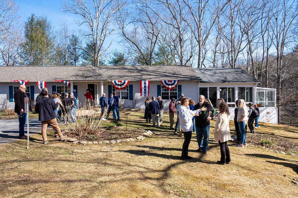 Veterans and neighbors gathered on the lawn in front of the farmhouse