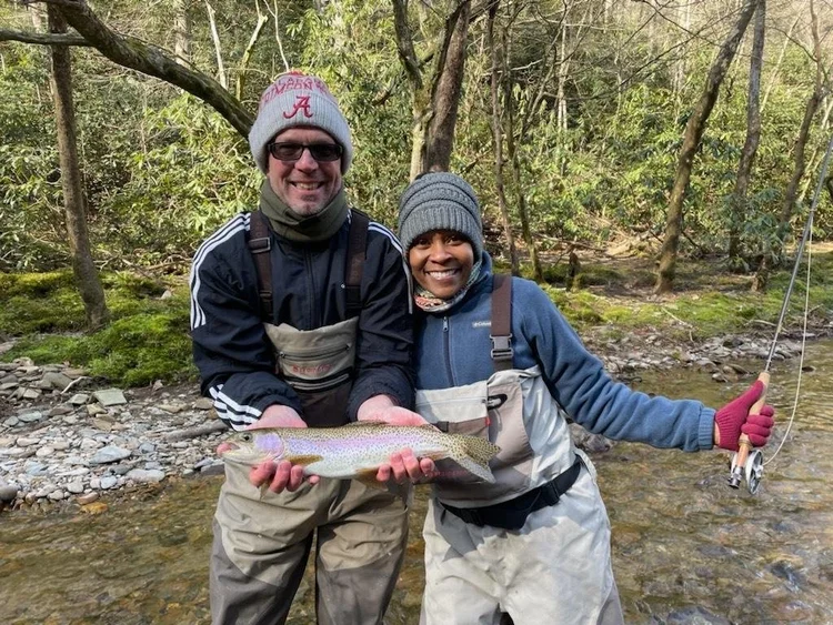 Two veterans holding up a trout on a fly fishing trip