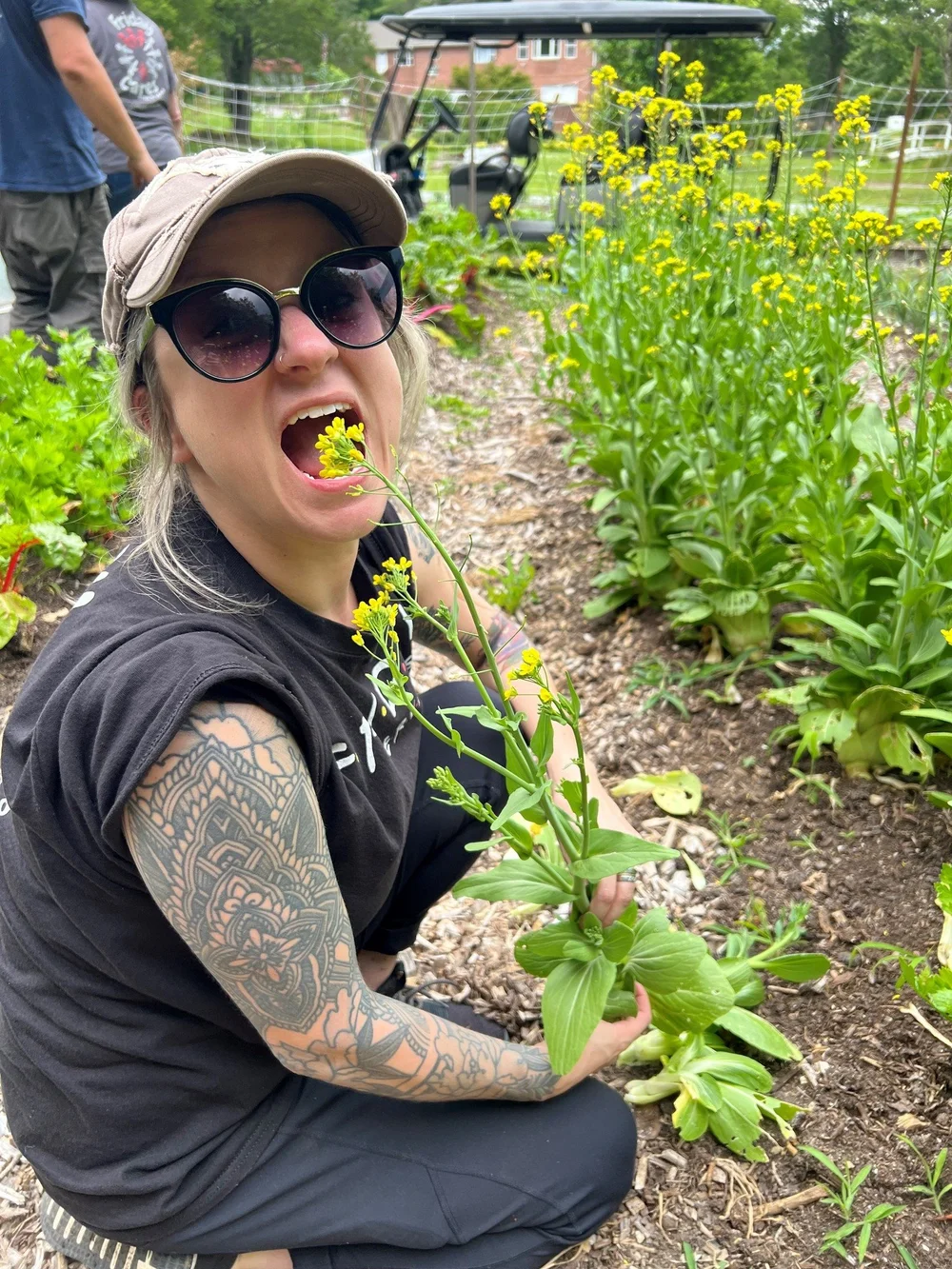 A smiling volunteer kneeling in the farm's flower garden