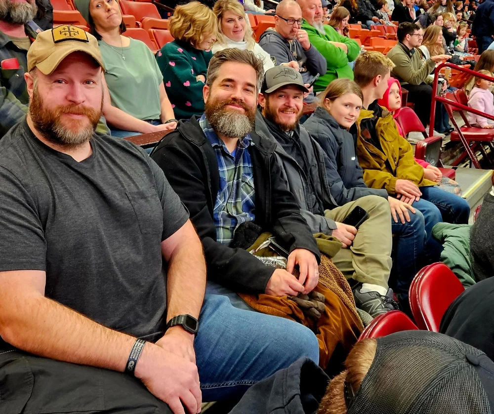 Veterans smiling together in the stands at a hockey game outing