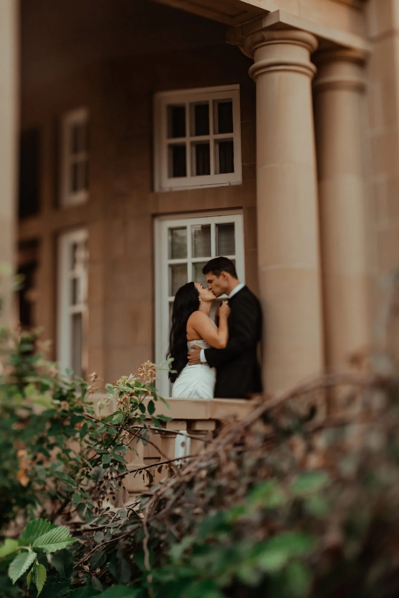 two lovers share a romantic kiss under the stone porch on Edmonton's Government house