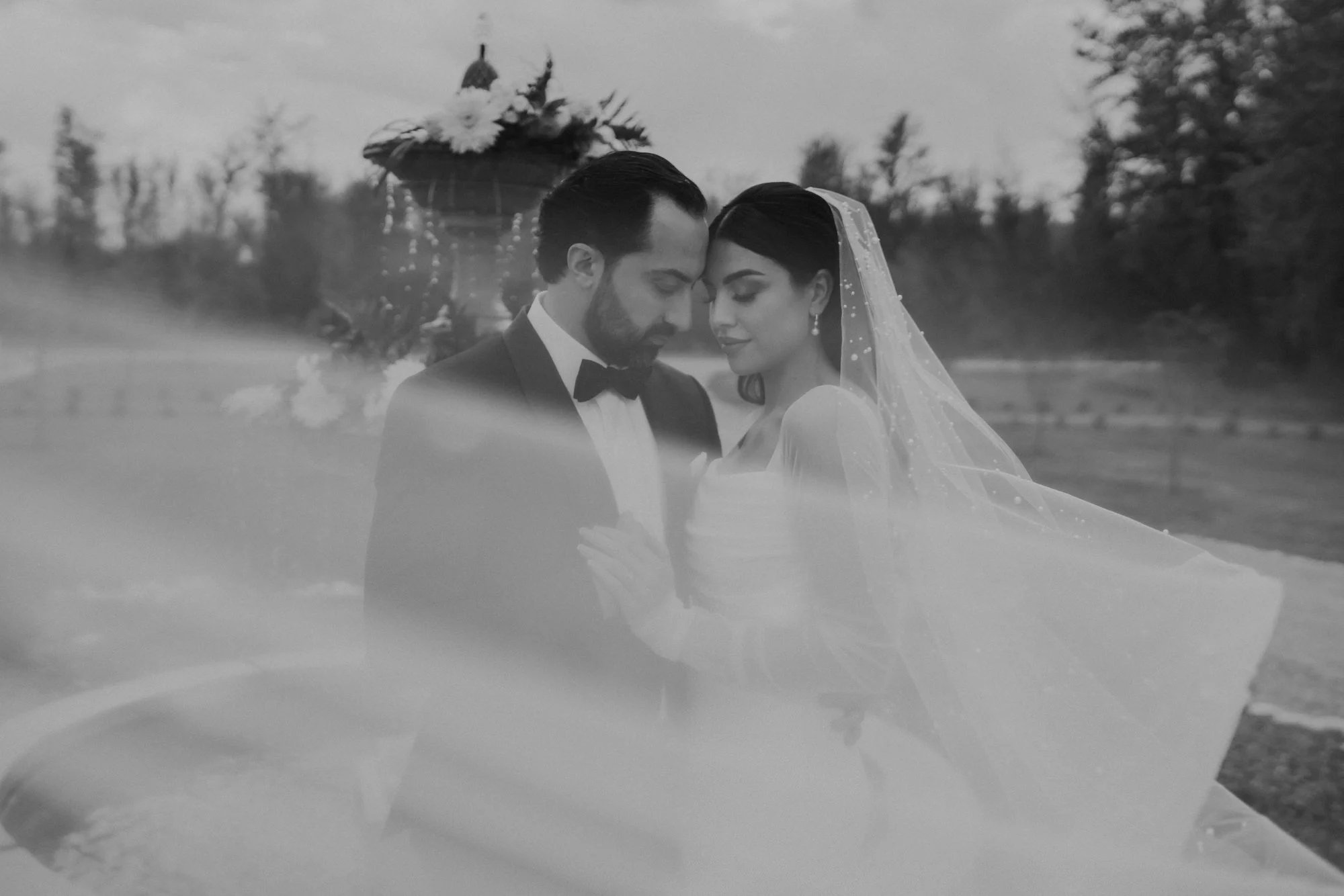 A bride and groom share an intimate moment in front of a fountain.