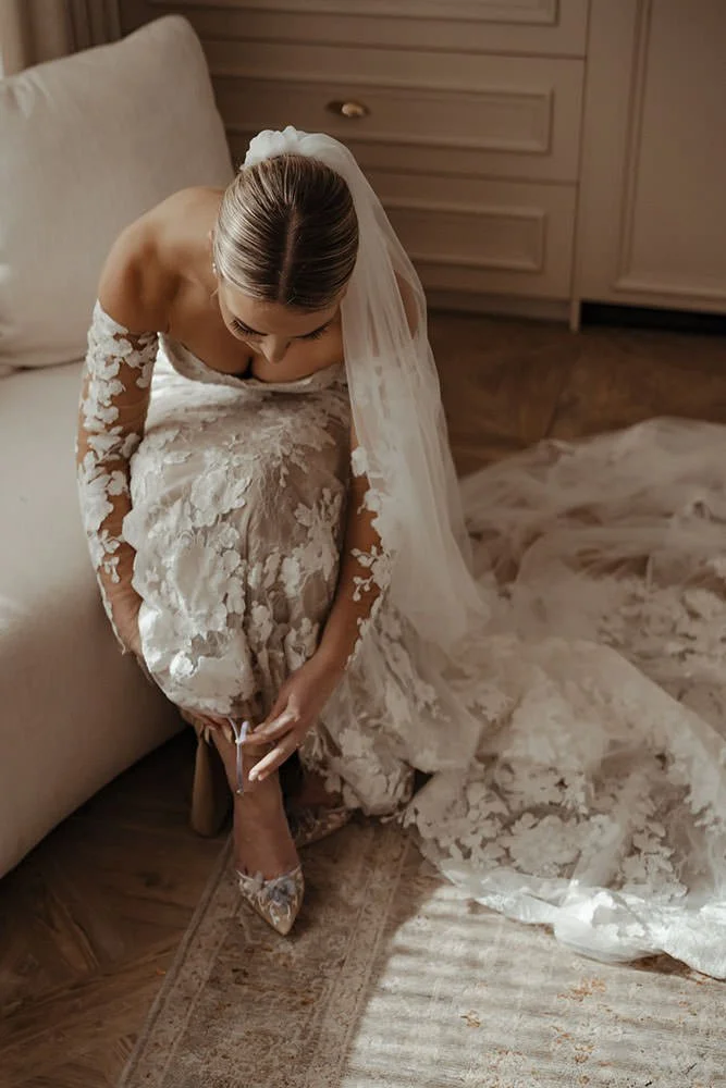 A bride puts her shoes on in a bridal suite.
