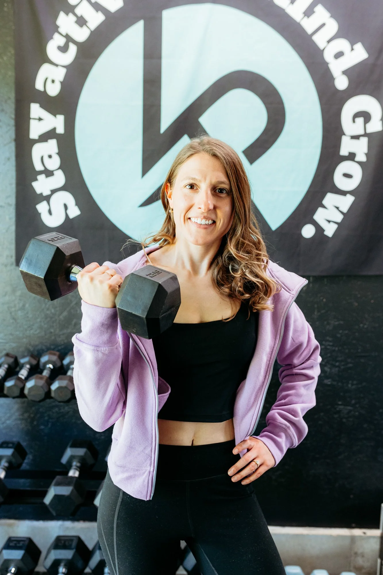 Kaylee pobocik, a physical therapist, holding a dumbbell and smiling at the camera inside her physical therapy clinic