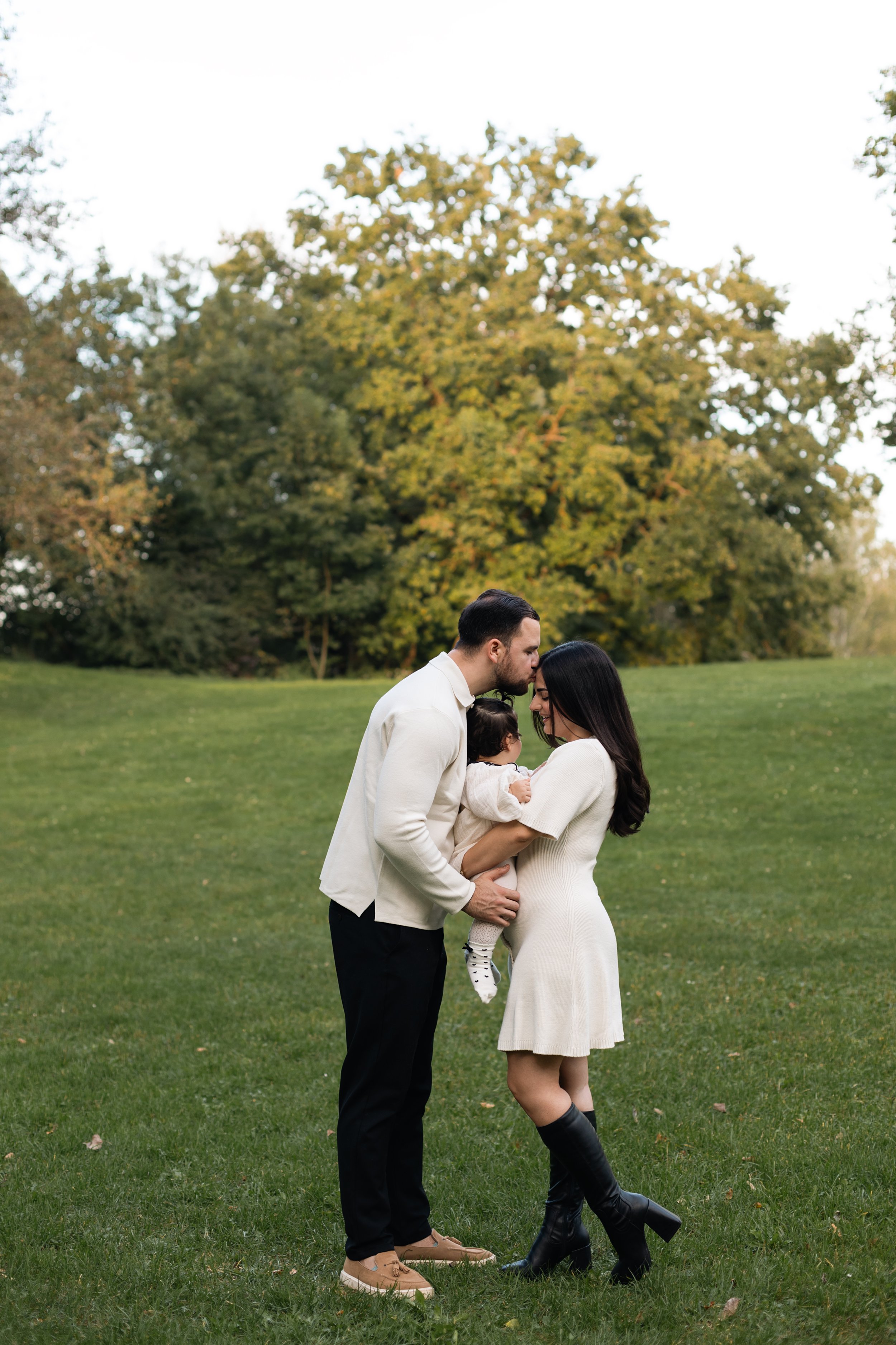 Familie sitzt dicht beieinander im Gras in Landshut, authentische und liebevolle Szene. Family sitting close together on grass in Landshut, authentic and loving scene.