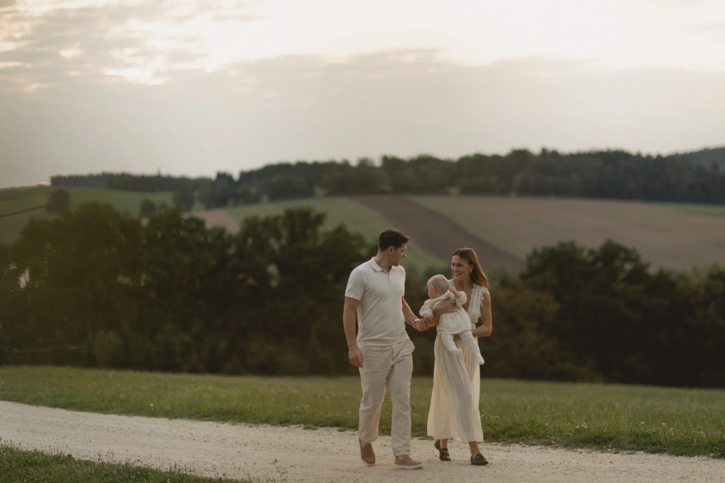 Familie hält sich an den Händen auf einer Wiese in Bayern, zeitlose und natürliche Familienbilder. Family holding hands on a meadow in Bavaria, timeless and natural family images.